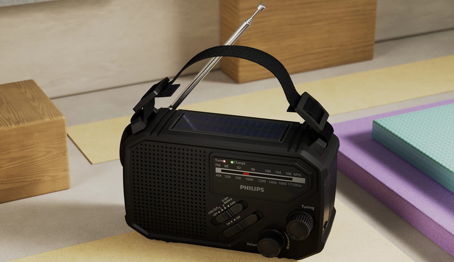 Una radio Philips negra con panel solar, asa y antena está sobre una superficie colorida, bloques de madera y almohadillas en el fondo.