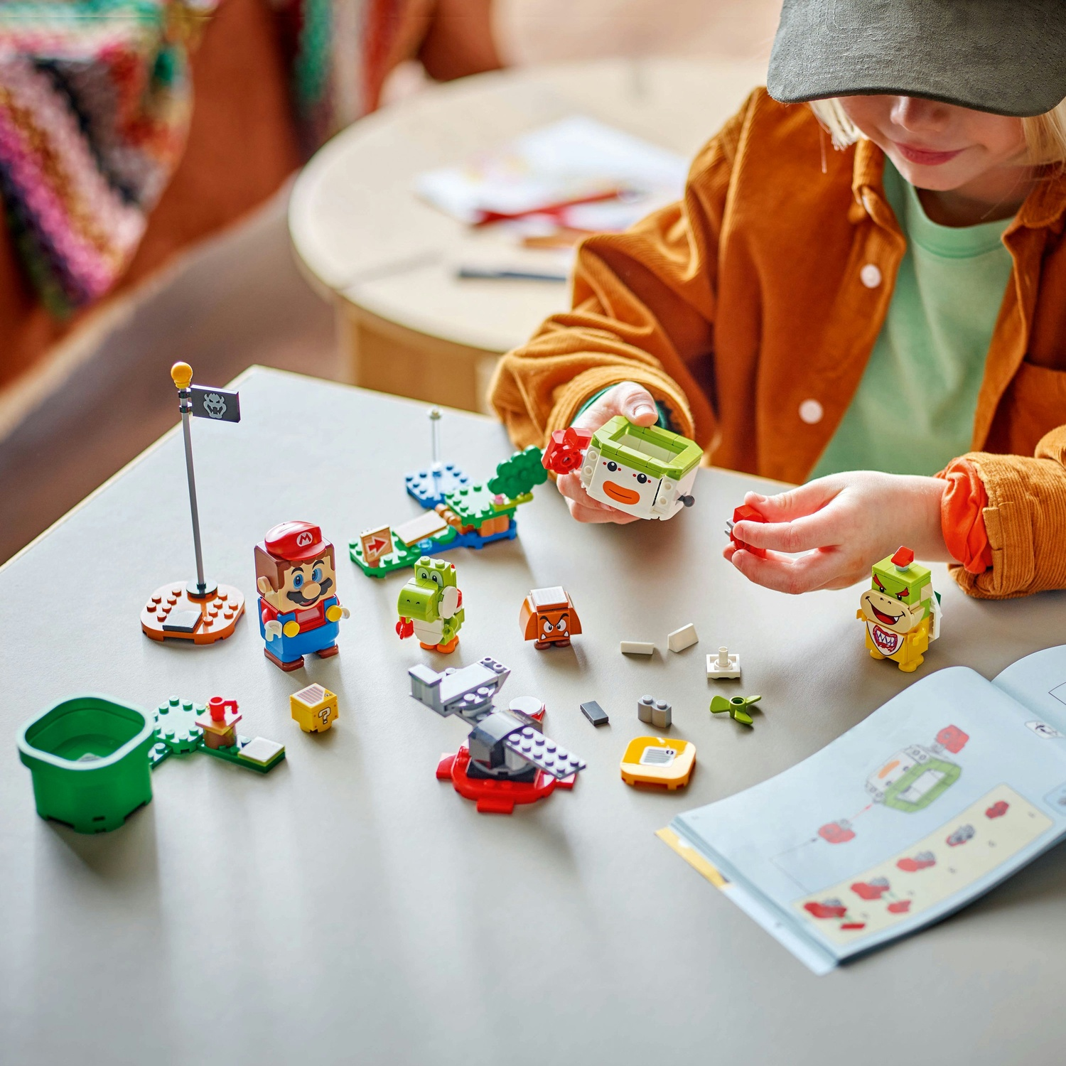 Un bambino sta costruendo un set Lego con Mario, Yoshi e altri personaggi. Il set è sparso su un tavolo grigio.