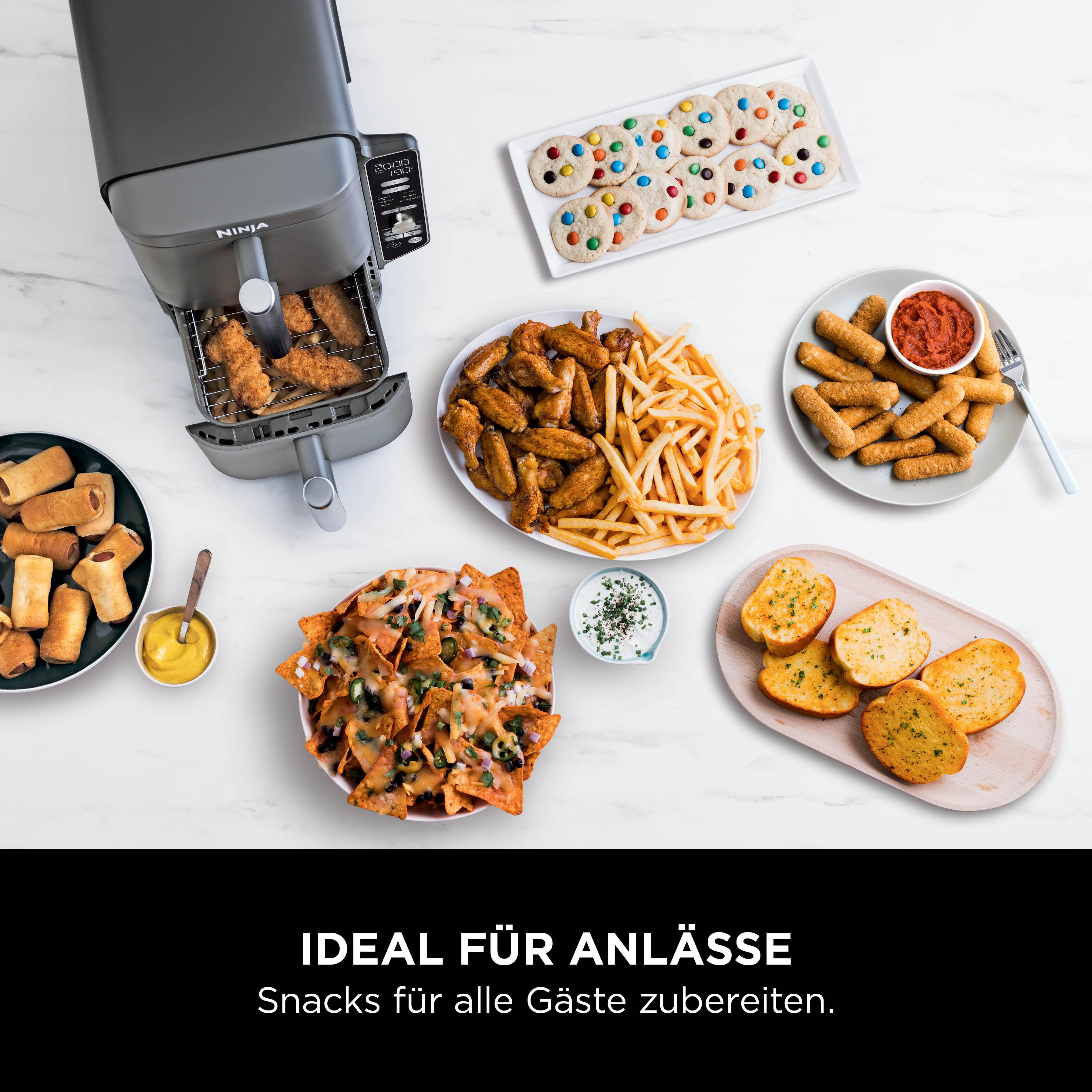 Ein Airfryer mit verschiedenen Snacks: Chicken Tenders, Pommes, Mozzarella-Sticks, Nachos, Wings, Kekse, Knoblauchbrot und Würstchen im Schlafrock.