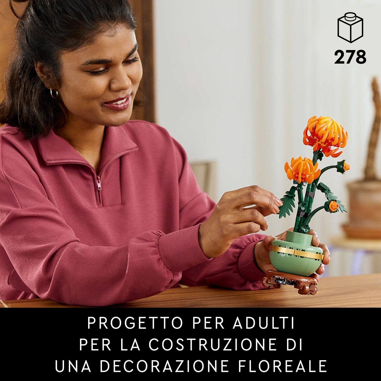Donna con set Lego di fiori. Il set ha fiori arancioni in un vaso verde. Il testo in basso dice 'Progetto per adulti'.