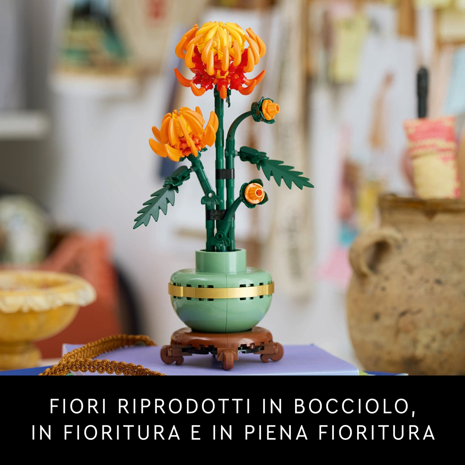 Una composizione floreale Lego con fiori arancioni, steli verdi e un vaso verde con una fascia dorata, su un supporto di legno.
