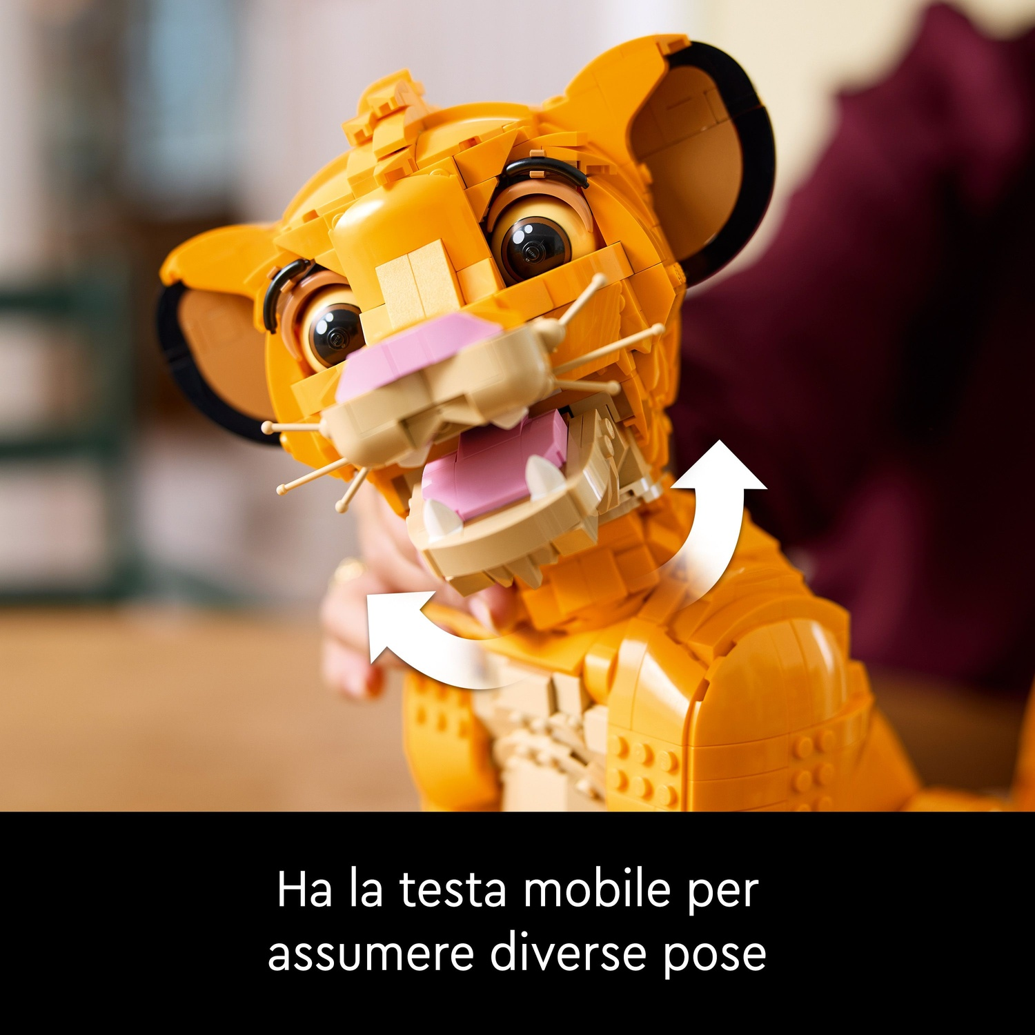 Un leone Lego con la bocca aperta. Il leone è giallo con la lingua rosa. Frecce indicano la mobilità della testa.