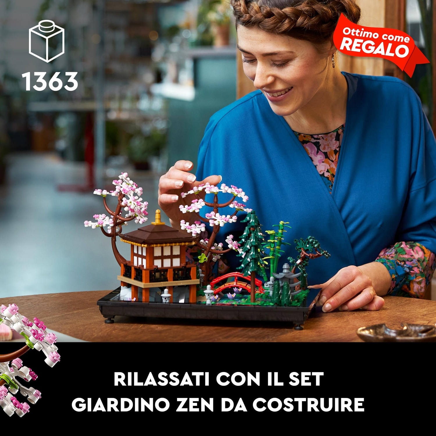 Una donna sorride, toccando un giardino zen Lego. Il set presenta un edificio, un ponte e alberi su una base nera.