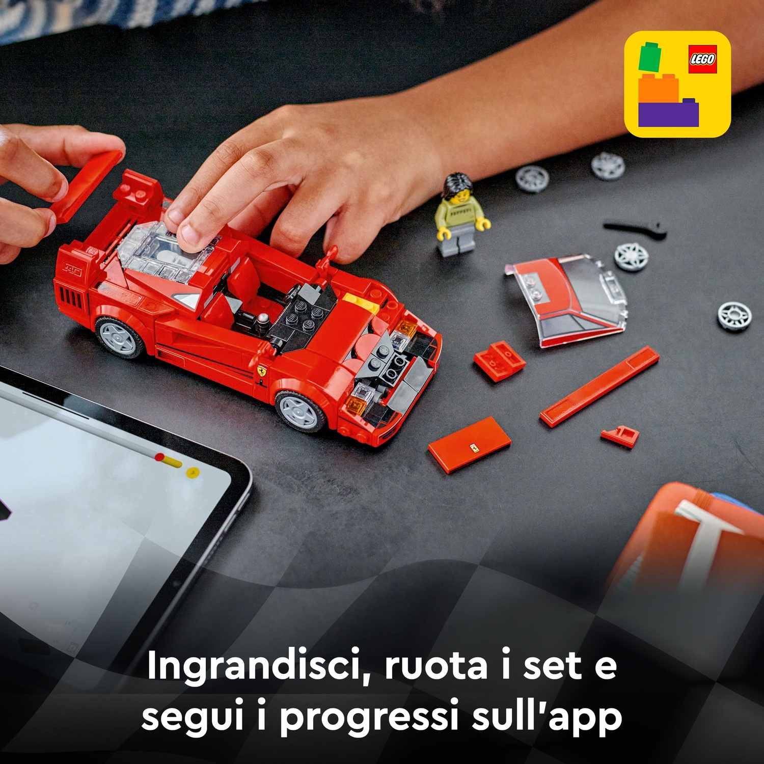 Mani assemblano una Ferrari Lego rossa. Parti e ruote sparse. Un tablet mostra un'interfaccia digitale.