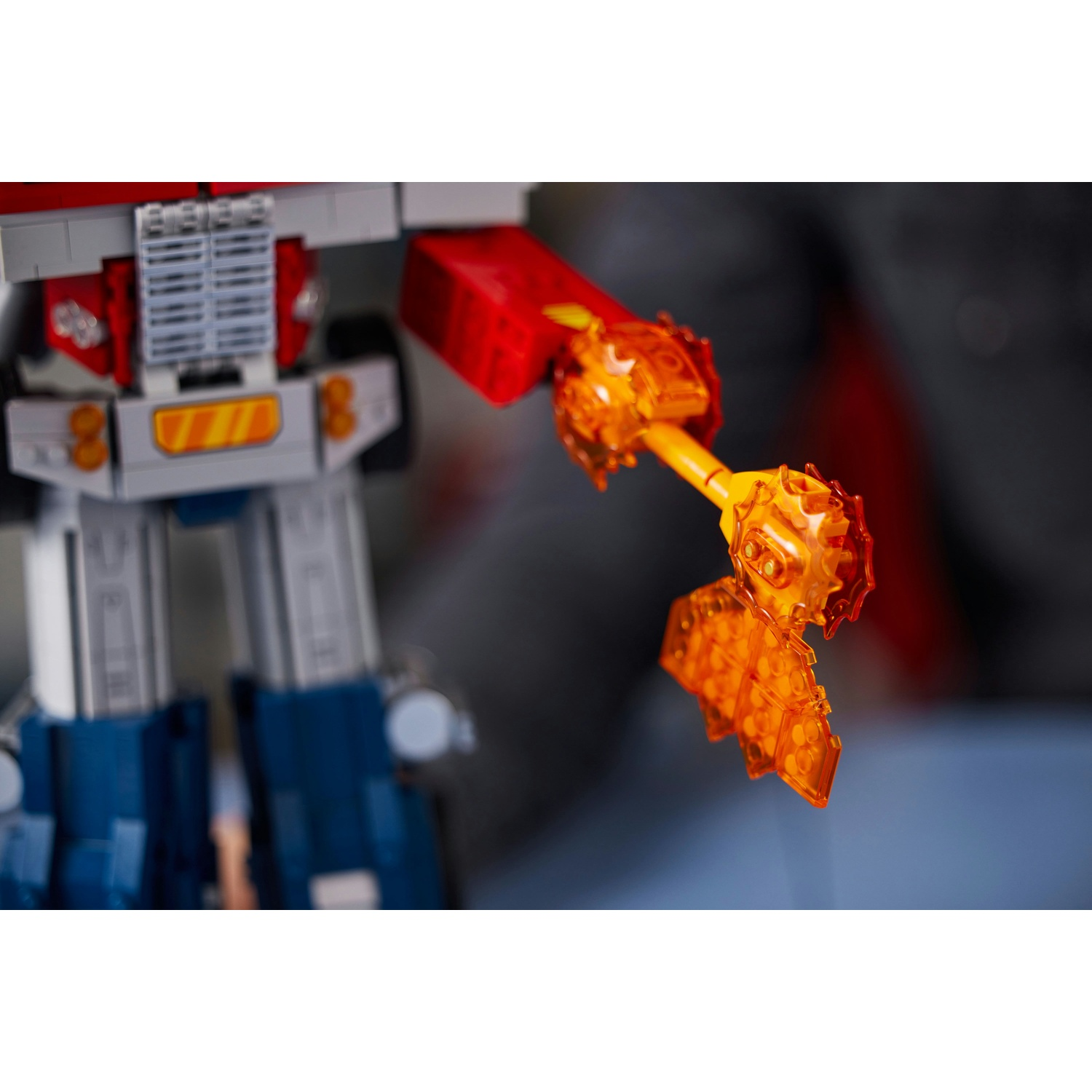 Un giocattolo Lego Optimus Prime con effetti energetici arancioni. Il giocattolo è rosso, blu e grigio. Gli effetti energetici sono arancioni traslucidi.