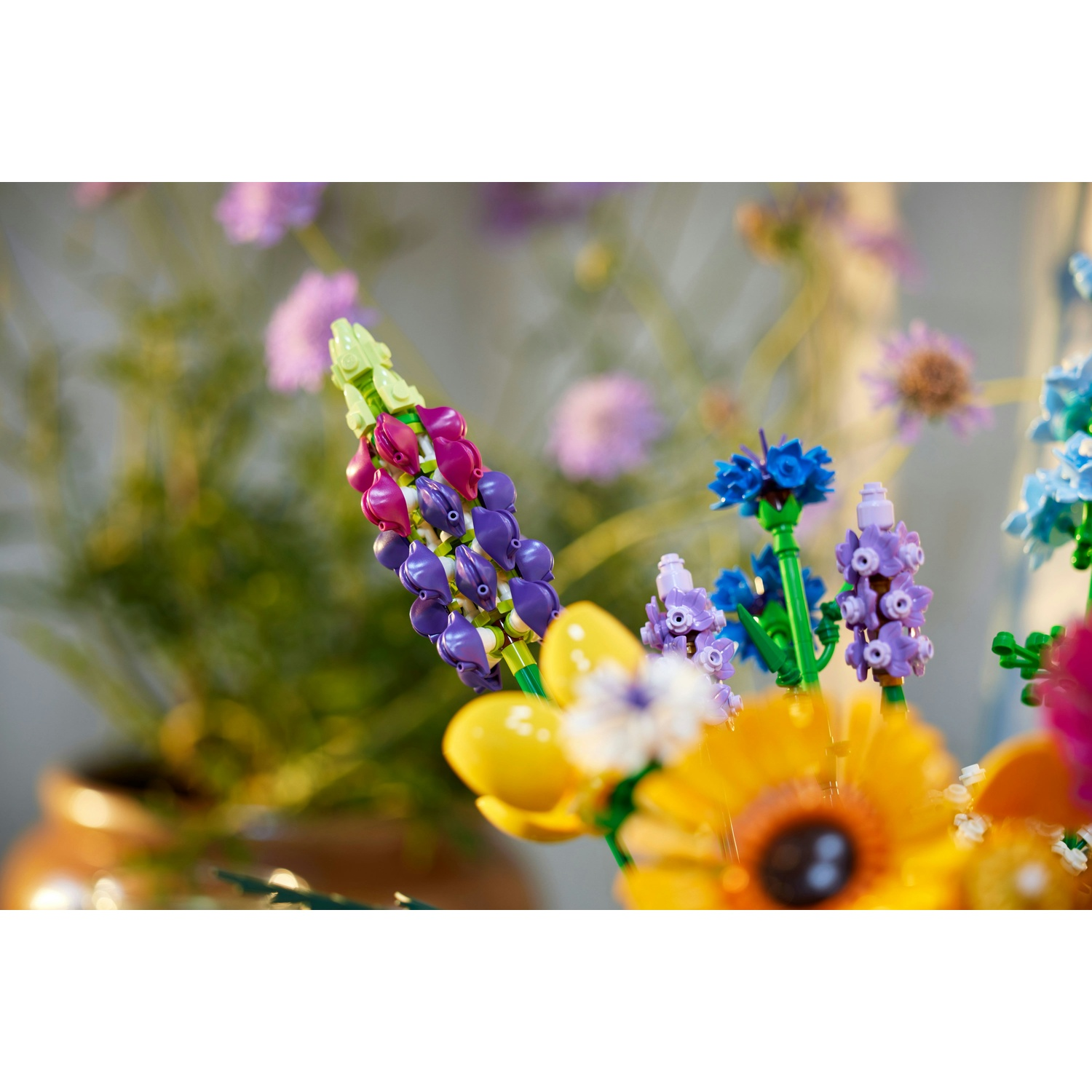 Primo piano di fiori Lego. Fiori viola, blu, gialli e bianchi in un vaso. Steli e foglie verdi. Sfondo sfocato.
