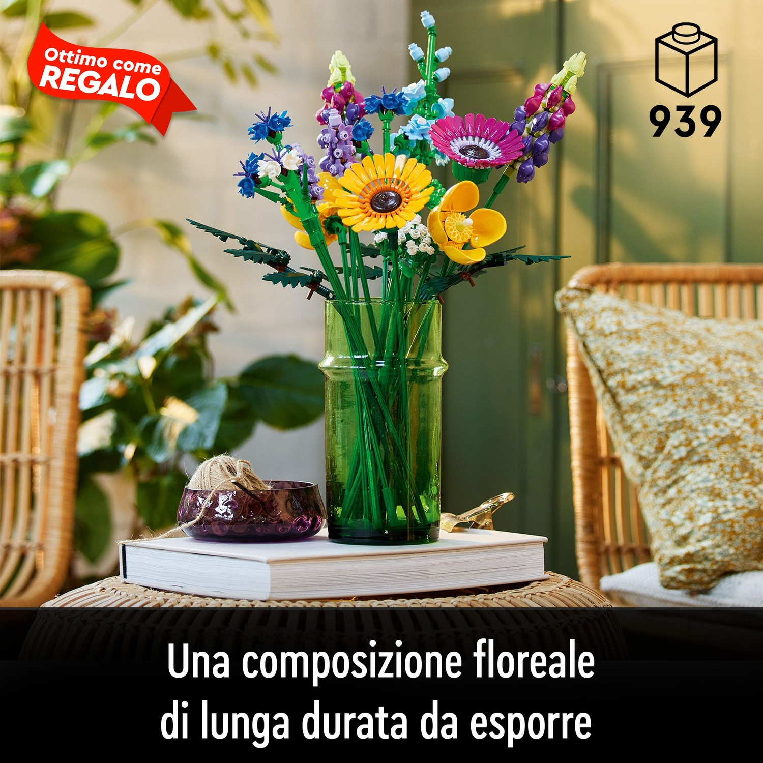 Fiori Lego colorati in un vaso verde su un tavolo. Una ciotola viola scuro e un libro sono anche sul tavolo. Sedia in vimini a sinistra.