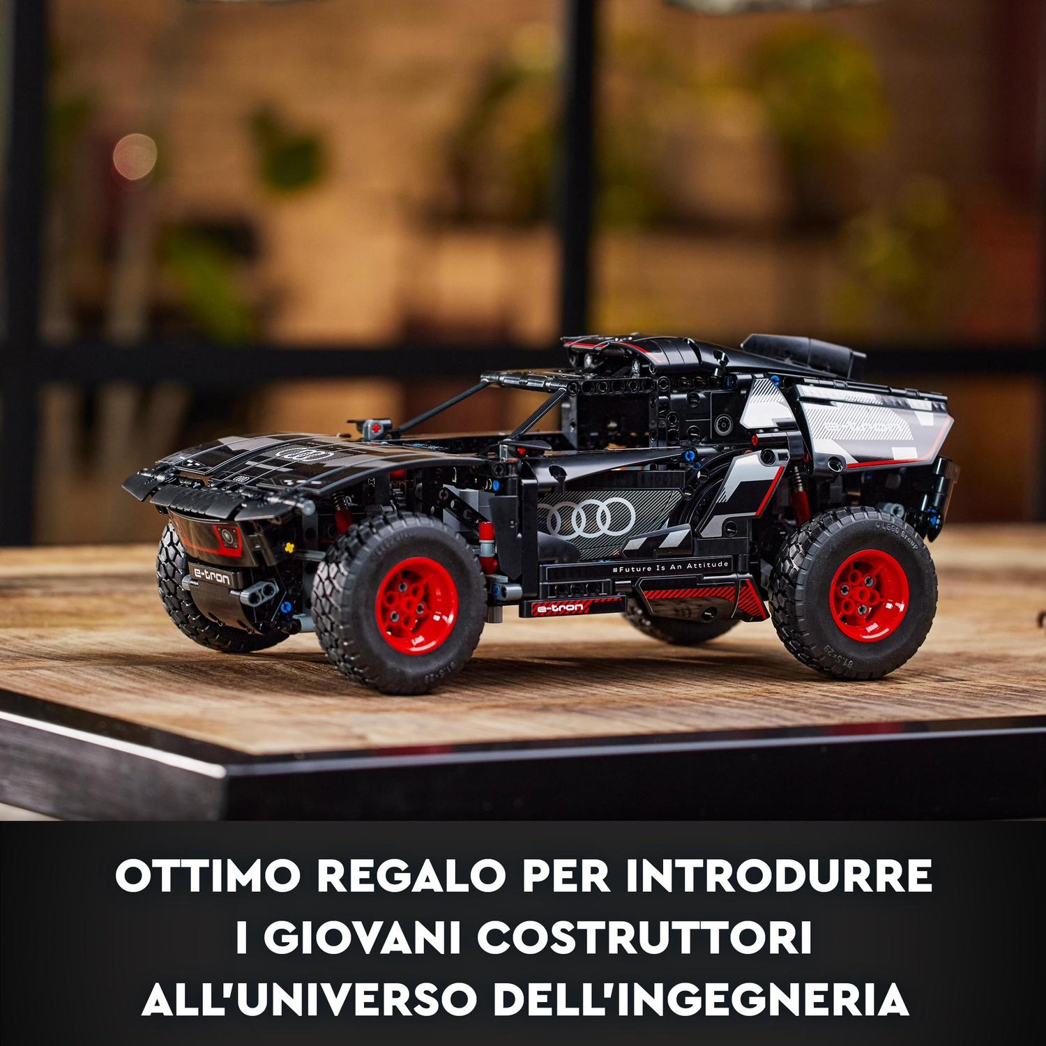 Un modello di auto Lego Audi e-tron nero con cerchi rossi su una superficie di legno. Lo sfondo è sfocato.