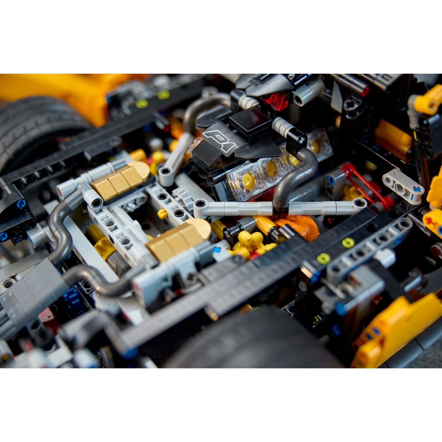 Primo piano di un motore di auto Lego. Include blocchi neri e gialli, tubi argentati e un blocco motore nero con il numero 1.