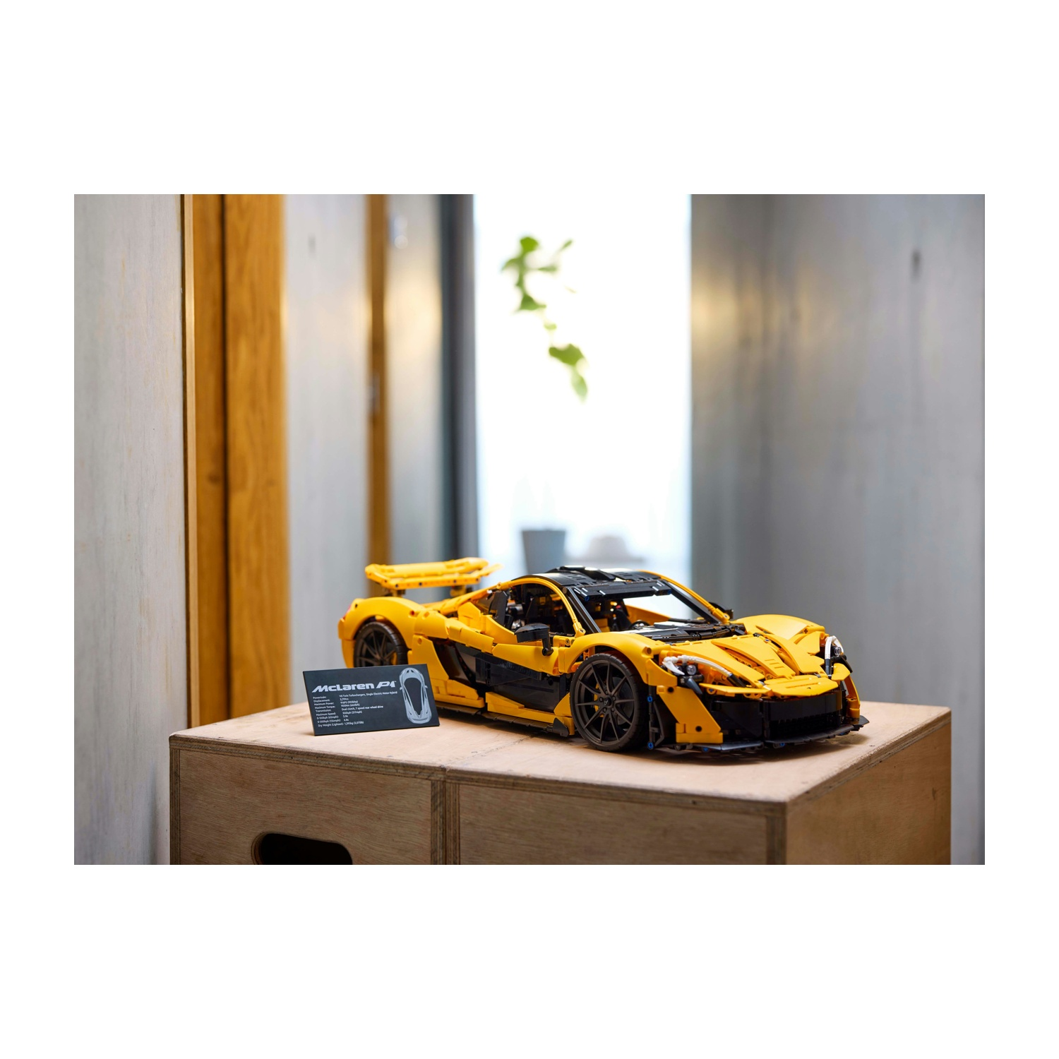 Un modello Lego McLaren P1 giallo e nero su una scatola di legno. Un cartello nero con specifiche è di fronte.