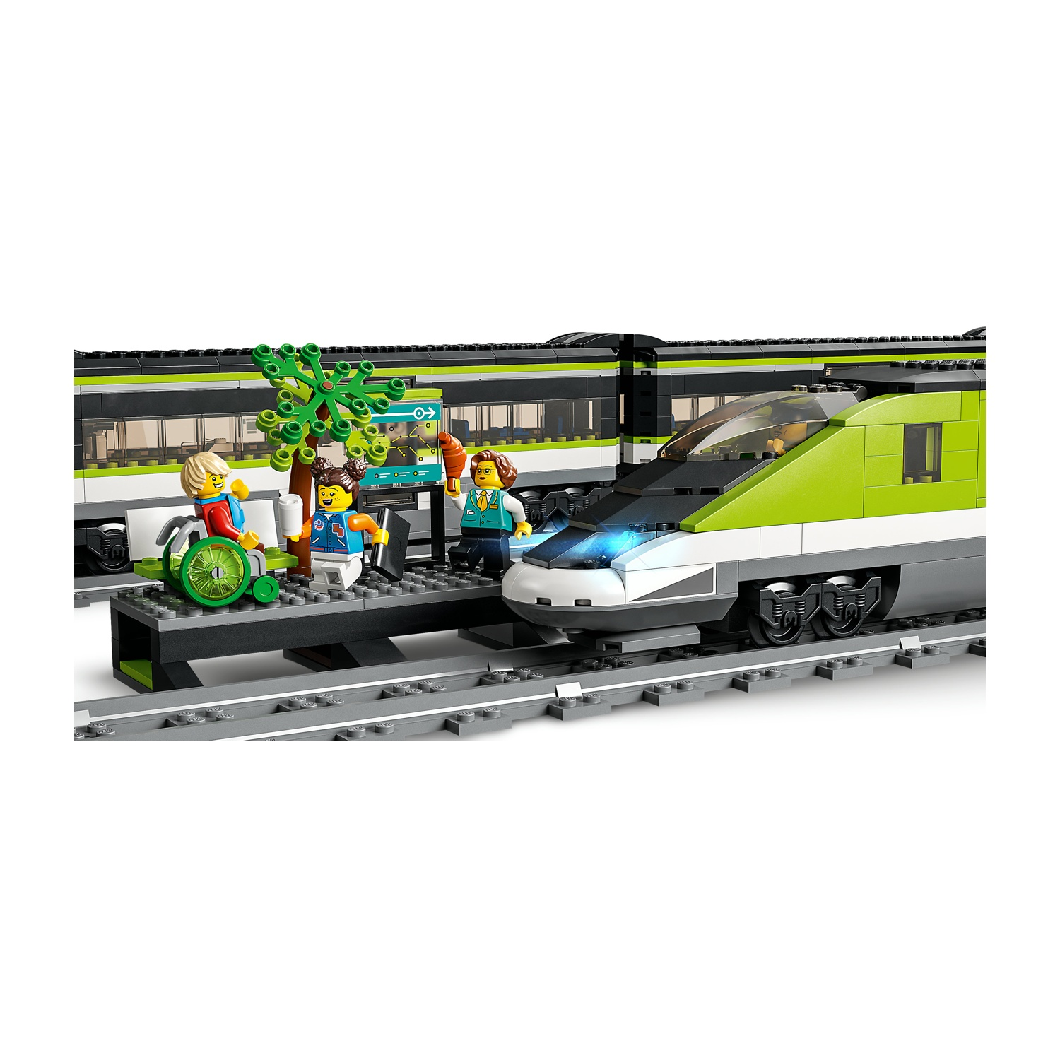 Set di treni Lego con treno, figure, albero e stazione. Persone vicino al treno. Colori verde e bianco. I binari sono davanti.