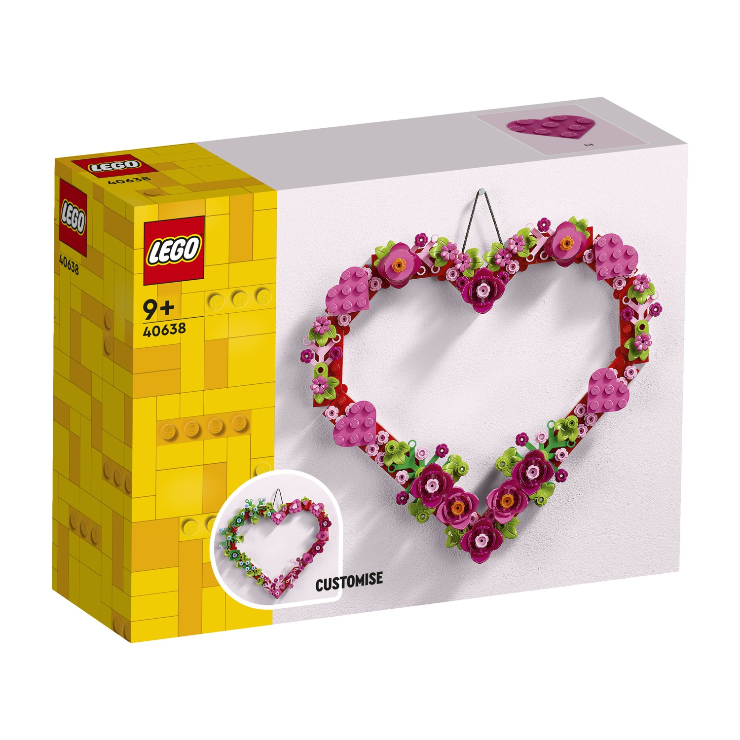 Una ghirlanda a forma di cuore Lego fatta di mattoncini Lego rosa e verdi. Appesa a una parete bianca.