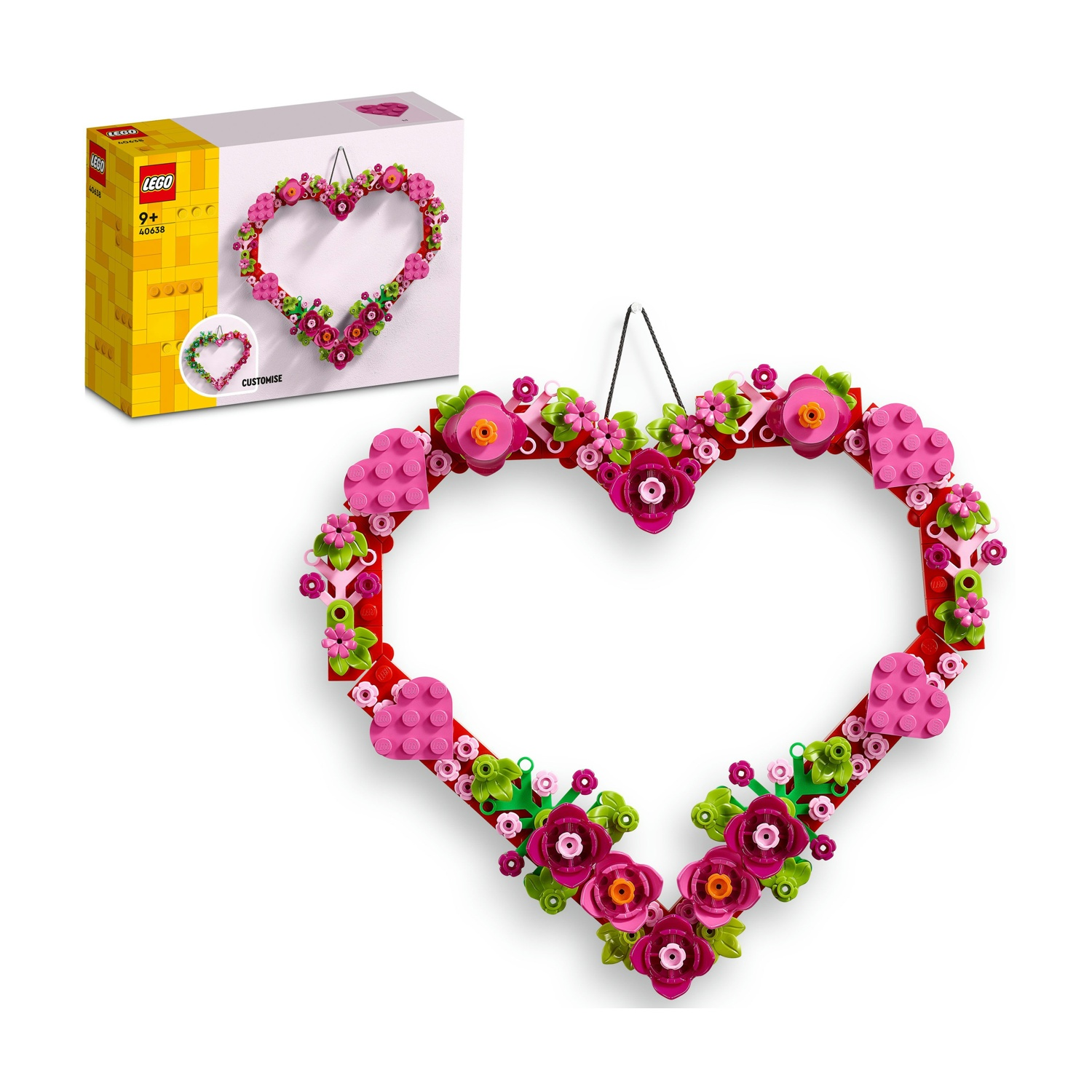 Una ghirlanda Lego a forma di cuore con fiori rosa, cornice rossa e foglie verdi. Una scatola Lego a sinistra.