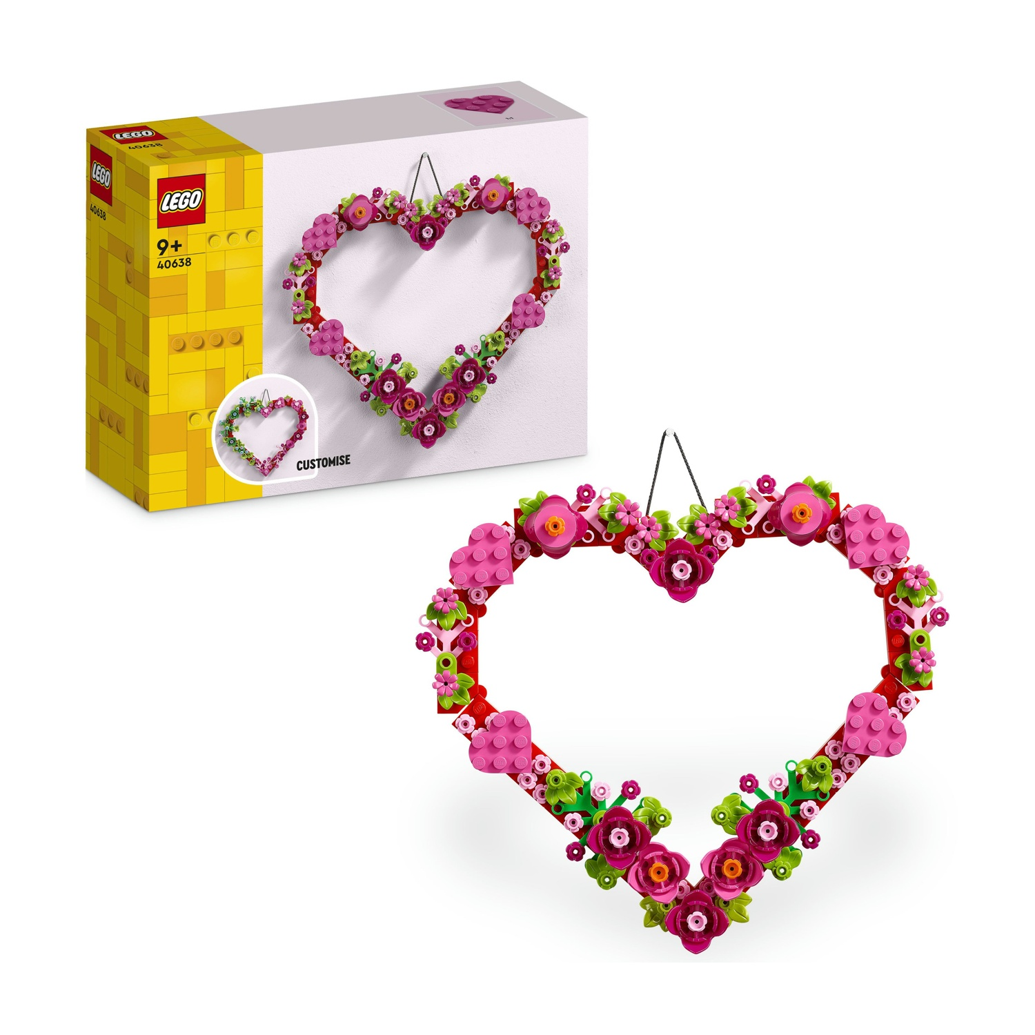 Una ghirlanda a forma di cuore Lego con fiori rosa, accanto a una scatola Lego. La scatola mostra il design della ghirlanda. Lo sfondo è bianco.