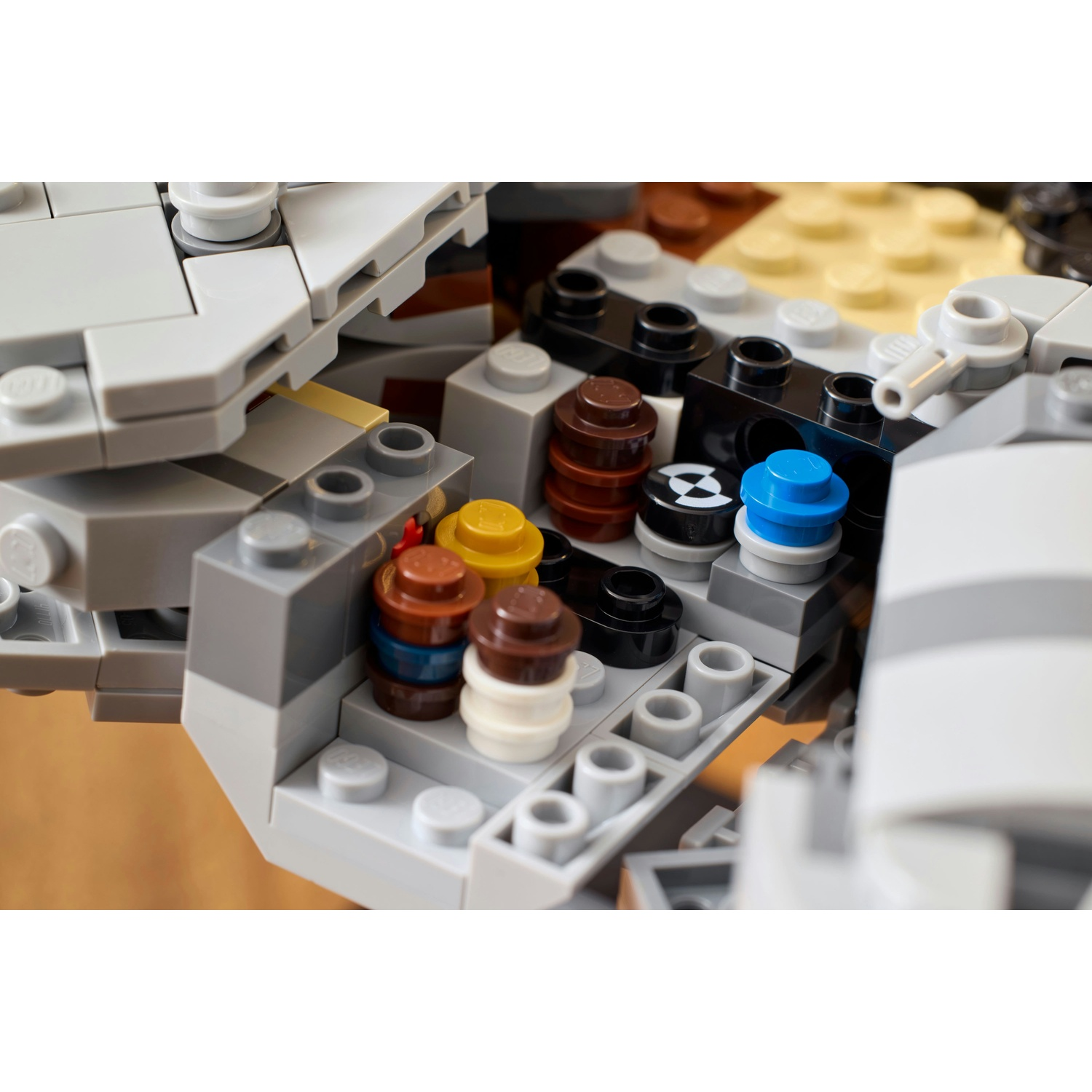 Primo piano di mattoncini Lego. Vari pezzi Lego rotondi colorati sono impilati, tra cui marrone, blu, giallo e bianco. Strutture Lego grigie li circondano.