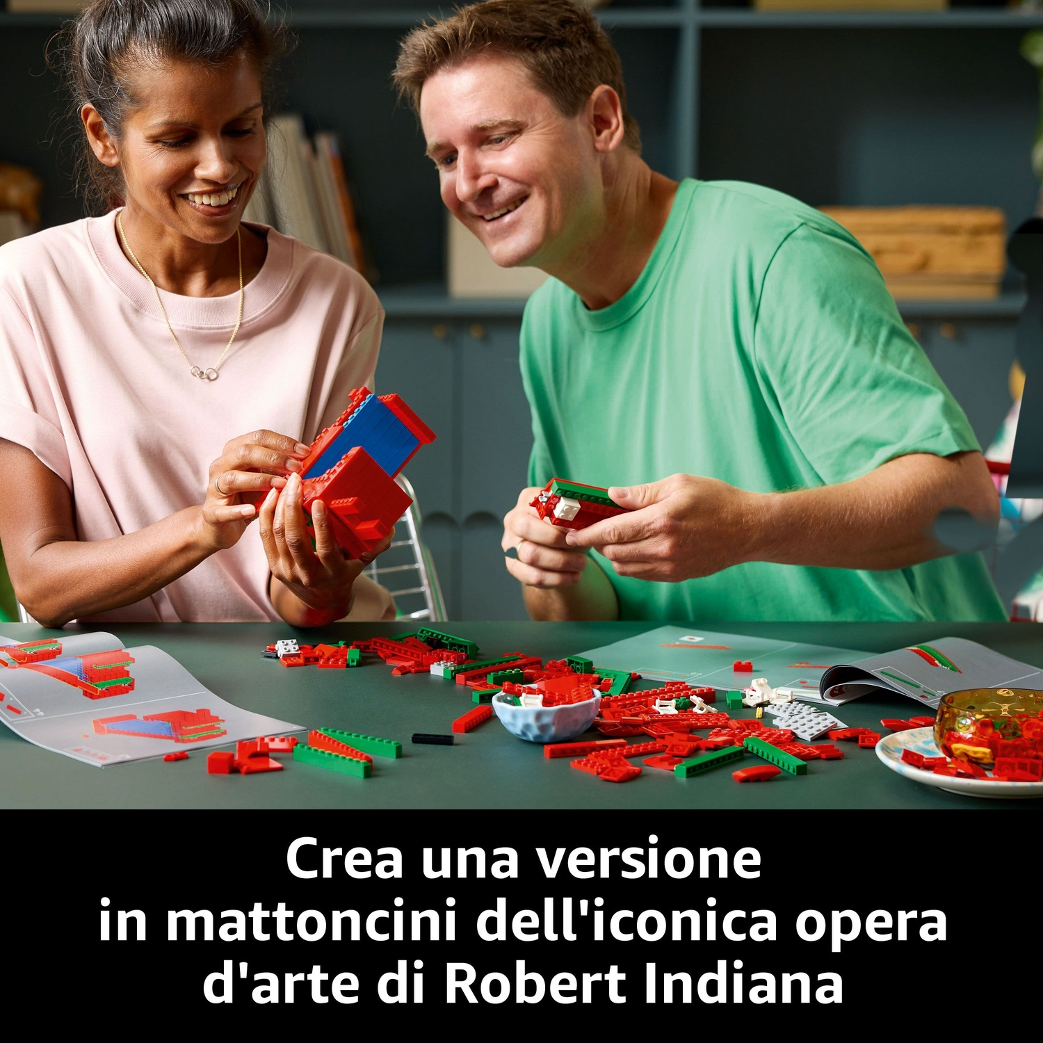 Un uomo e una donna stanno costruendo con i mattoncini Lego. Mattoncini rossi e verdi sul tavolo. La donna indossa una maglietta rosa, l'uomo una verde.