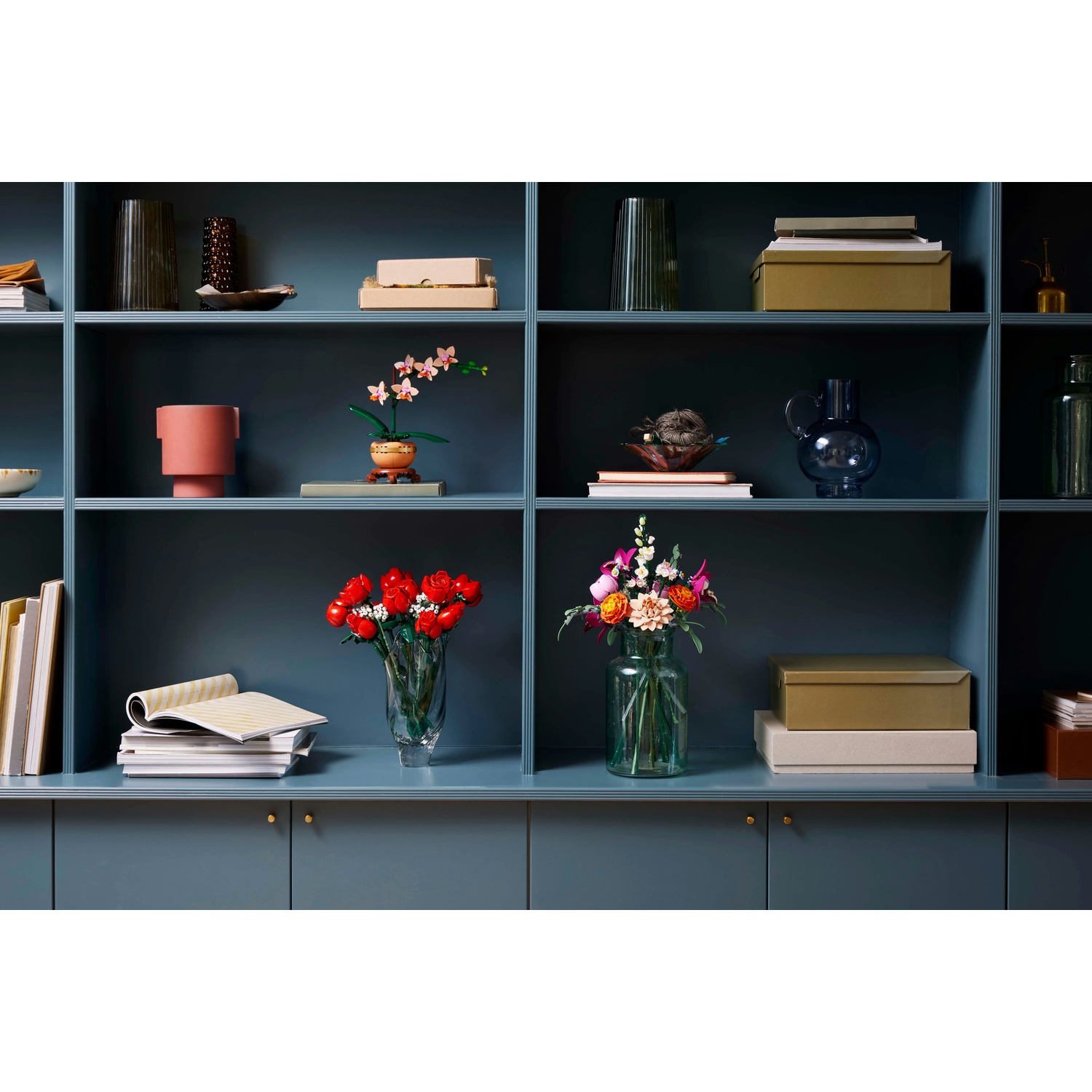 Un mobile blu scuro con vari oggetti sugli scaffali. Include vasi con fiori, libri, scatole e oggetti decorativi.