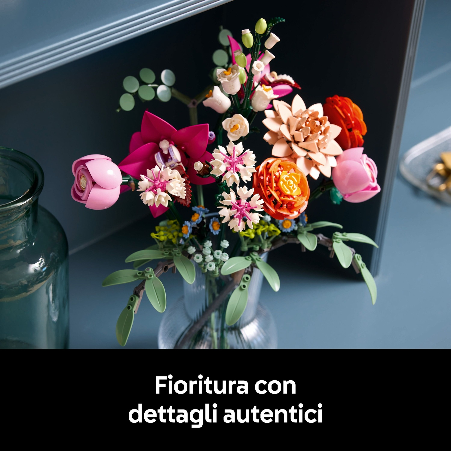 Un colorato bouquet di fiori Lego in un vaso di vetro. I fiori includono fiori rosa, arancioni e bianchi con foglie verdi.