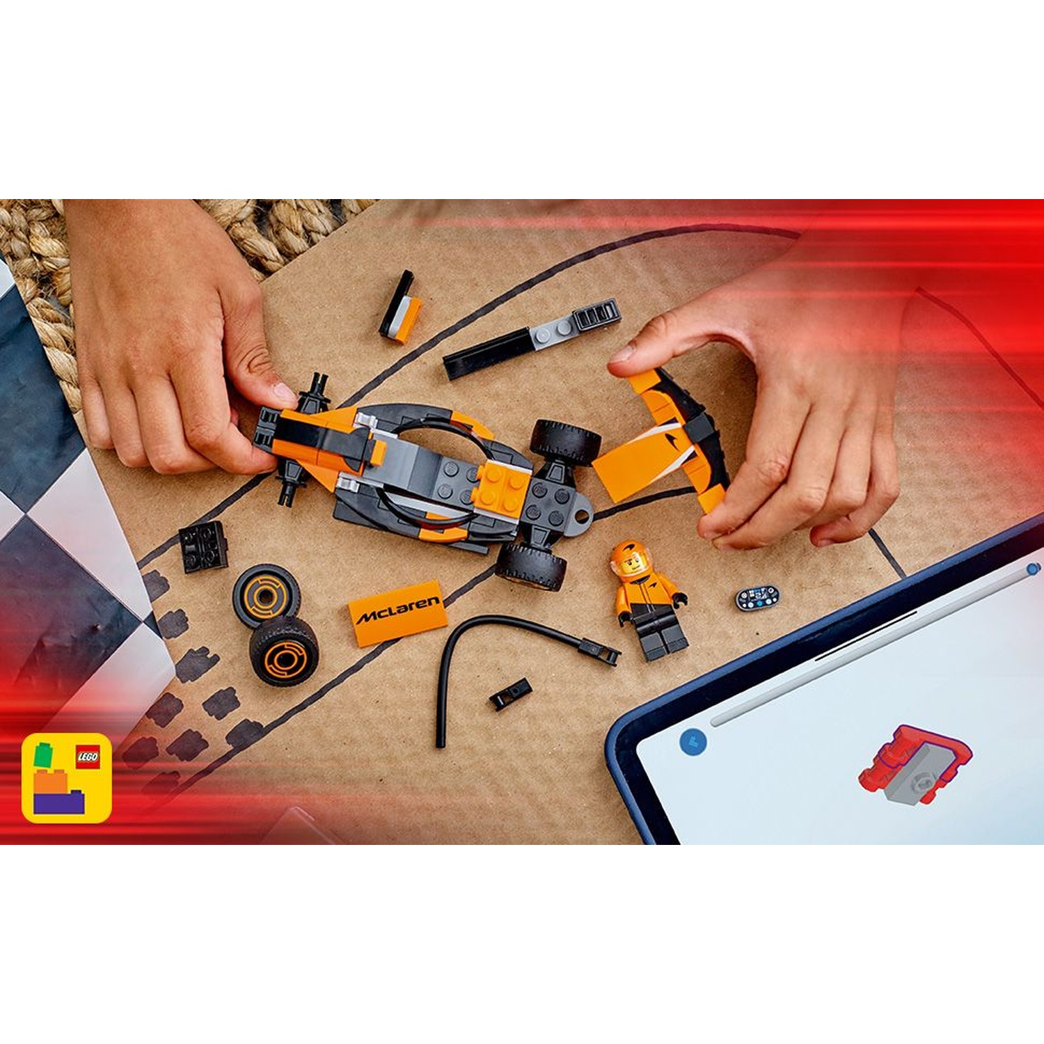 Mani che assemblano una McLaren Lego. Parti, ruote, una minifigure e un tablet con istruzioni sono visibili.