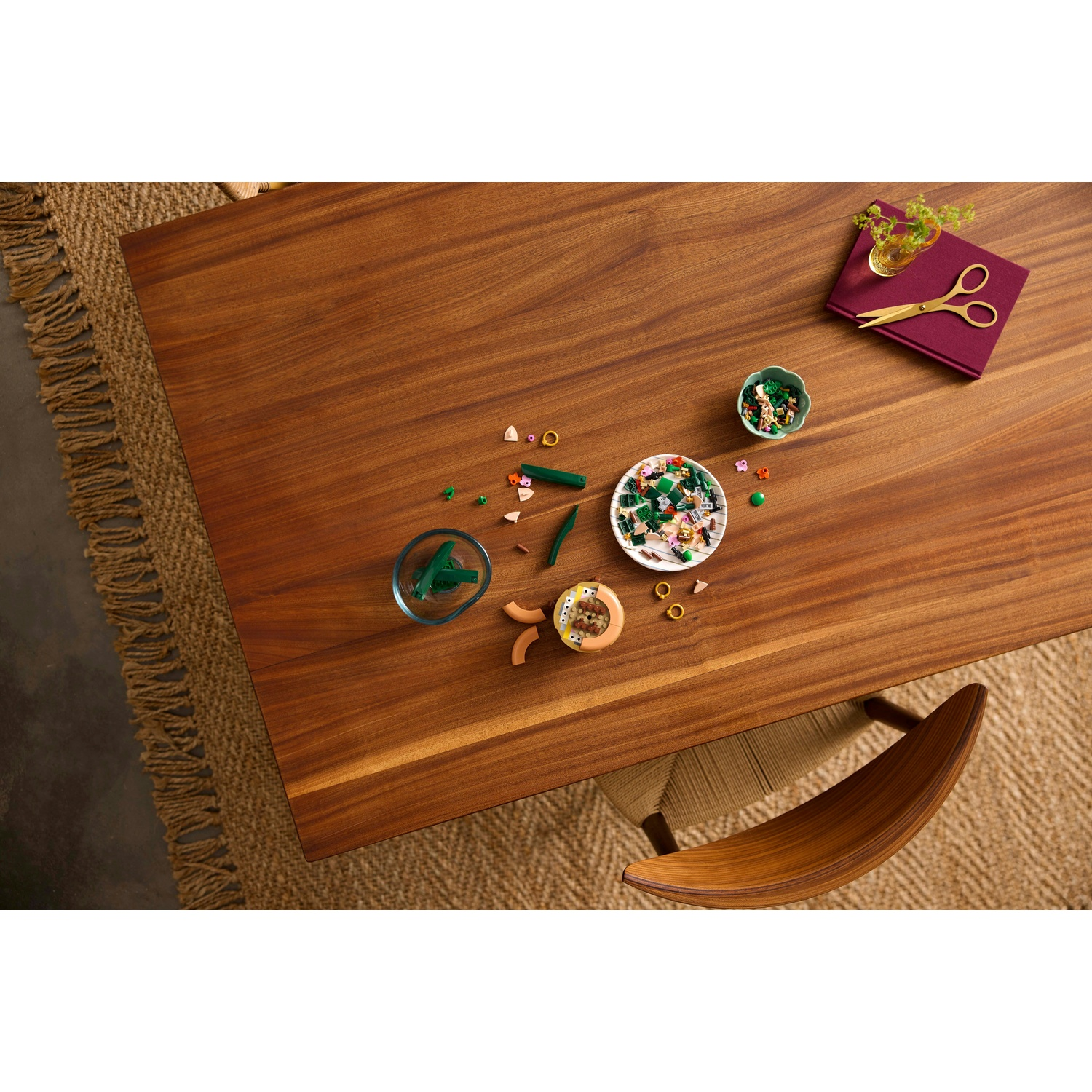 Tavolo in legno con vari oggetti. Include una ciotola di oggetti, forbici e una sedia. Un tappeto è visibile sotto.