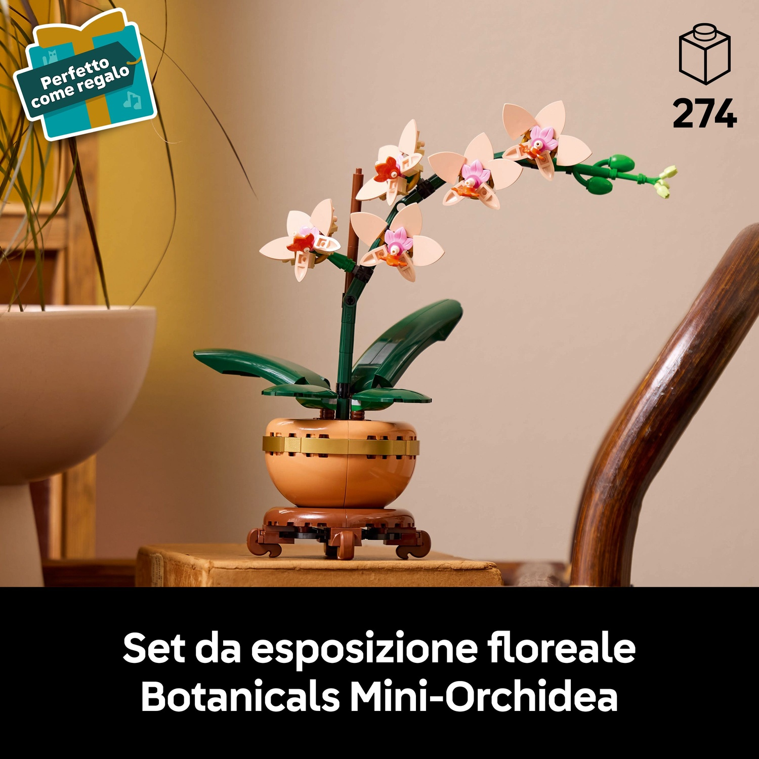 Un modello di orchidea Lego in un vaso marrone, con fiori rosa e bianchi. È su un supporto di legno. Un'etichetta regalo a sinistra.