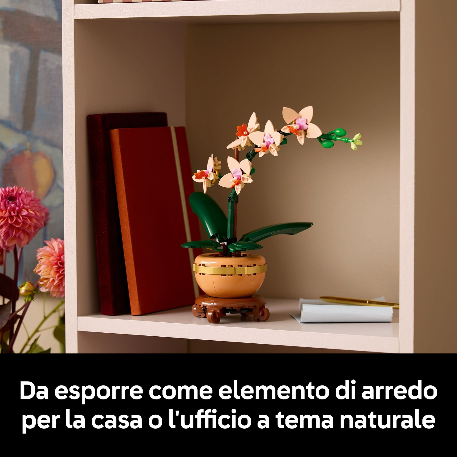 Una mensola mostra un'orchidea Lego, due libri, una penna e una carta arrotolata. Lo sfondo presenta un dipinto e fiori.