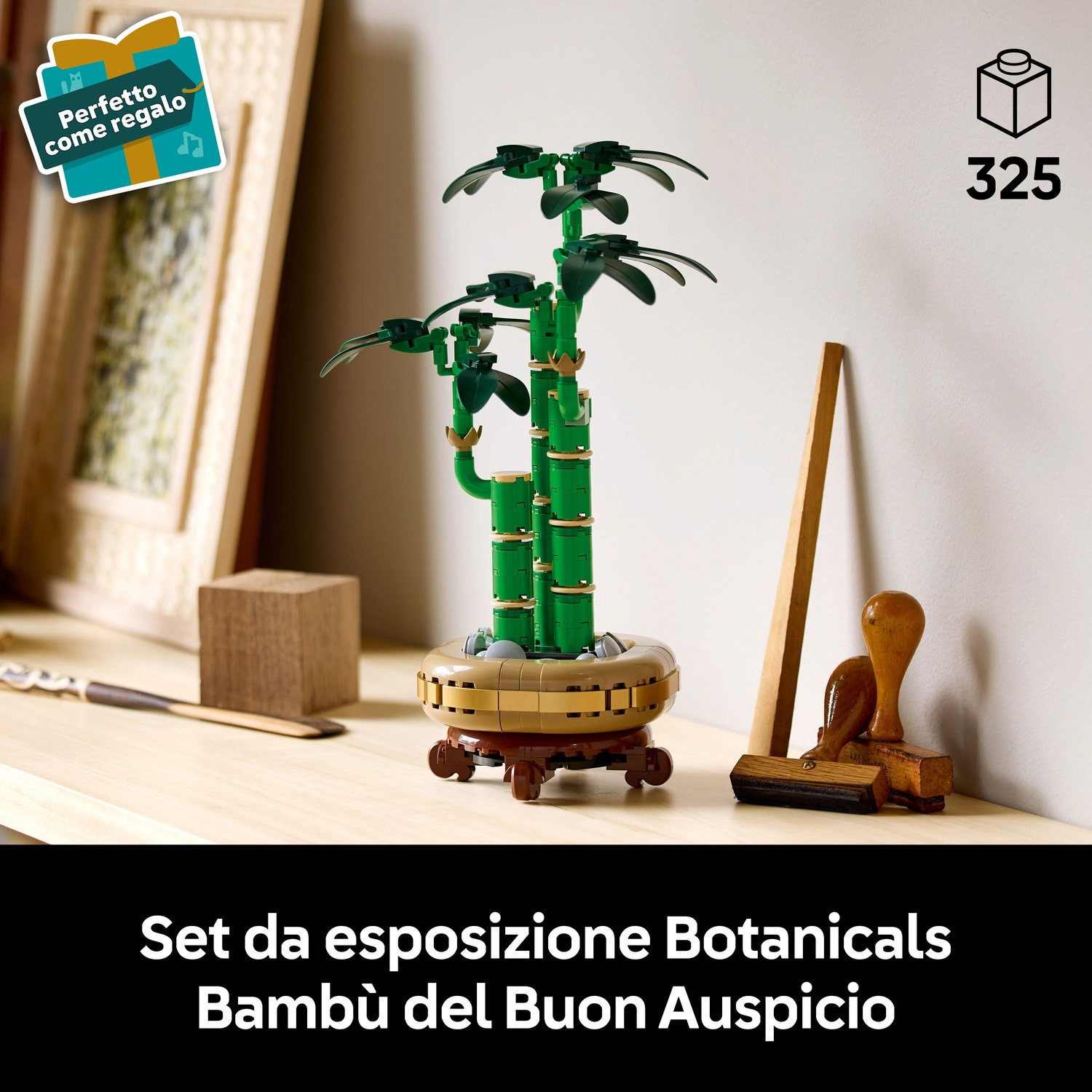 Un set Lego Bonsai su un tavolo di legno. Sono presenti anche un'etichetta regalo, un blocco di legno, un timbro e una cornice.