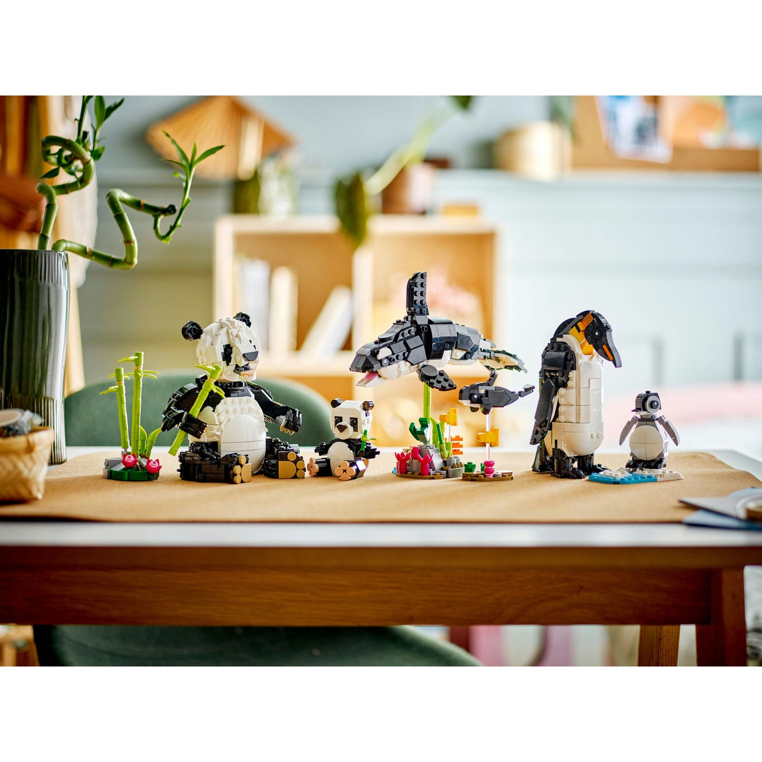 Set di animali Lego: panda, orca, pinguino e baby pinguino. Sono su un tavolo con bambù e altri elementi di sfondo.
