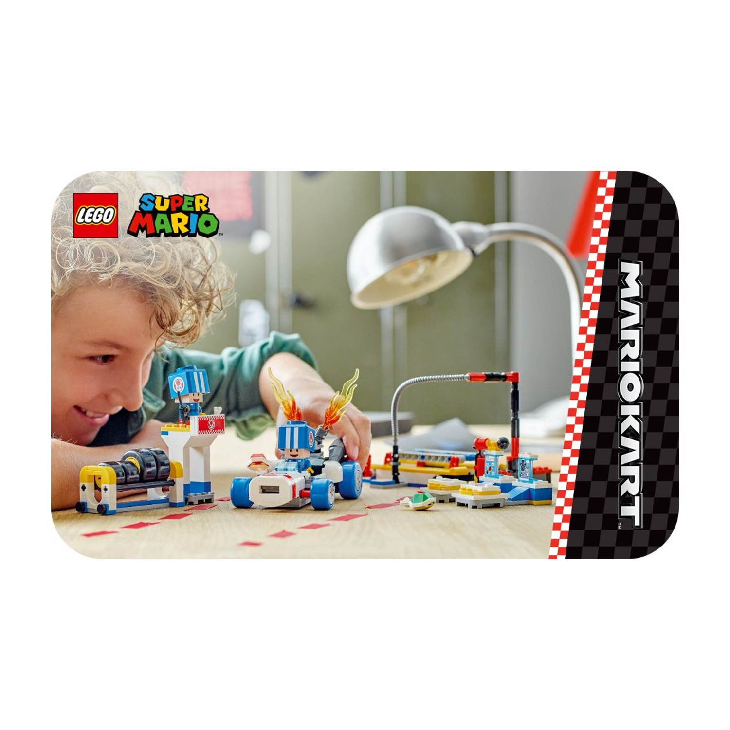 Un bambino gioca con un set LEGO di Super Mario. Il set include un'auto da corsa, una linea di partenza e altri accessori.