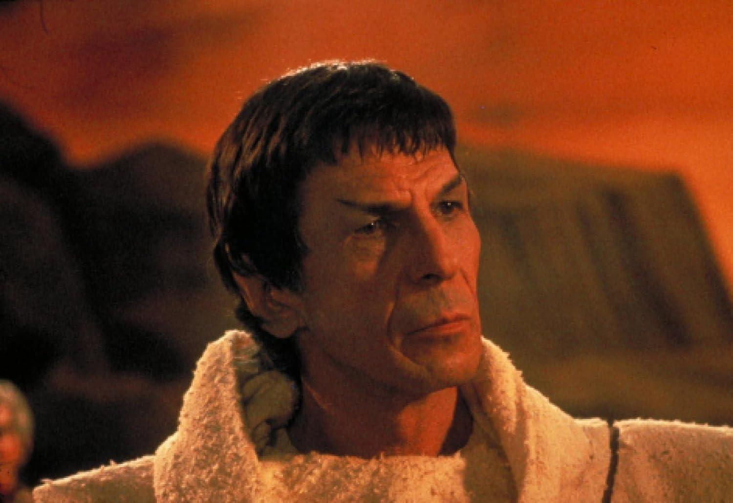 Leonard Nimoy als Spock. Er hat spitze Ohren und einen ernsten Ausdruck und trägt eine weiße Robe vor rotem Hintergrund.