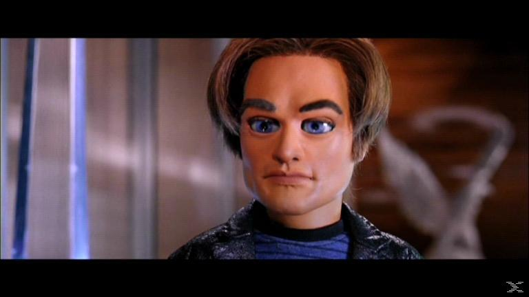 Eine Puppe mit blauen Augen und braunen Haaren blickt nach links. Sie trägt eine schwarze Jacke und ein blaues Hemd.