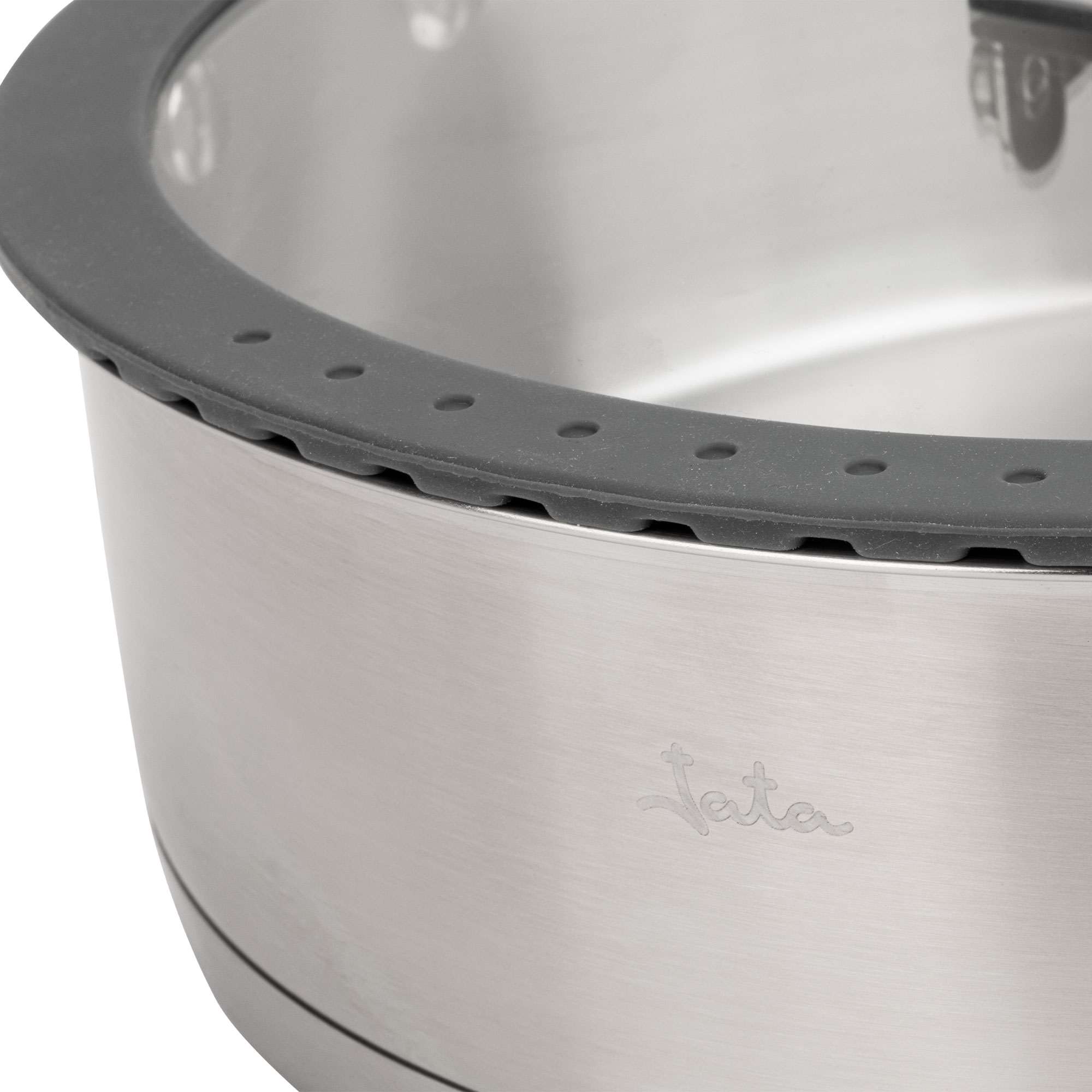Primer plano de una olla de acero inoxidable con borde gris. La olla tiene el logo 'Jata' grabado.