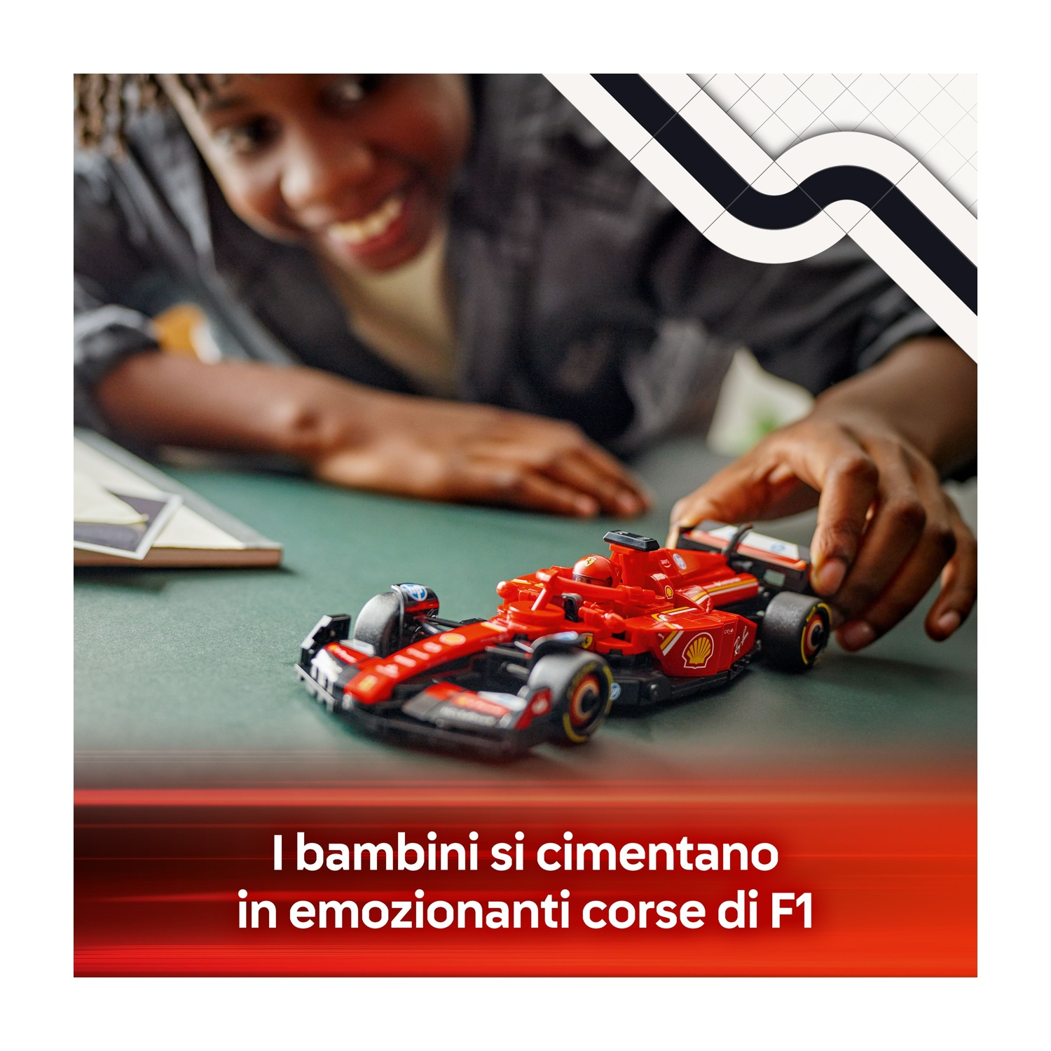 Un bambino gioca con un'auto giocattolo di Formula 1 rossa. L'auto è su una superficie verde. Testo: Bambini in competizione in emozionanti gare di F1.