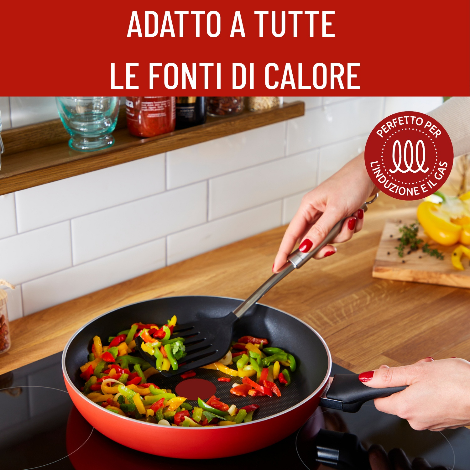 Una persona cucina peperoni colorati in una padella rossa su un fornello nero, usando una spatola nera. Lo sfondo include articoli da cucina.