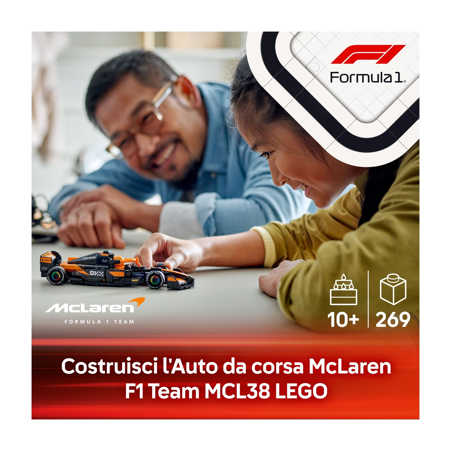 Un padre e una figlia stanno costruendo un set LEGO McLaren F1. L'auto è nera e arancione. Il logo è visibile.