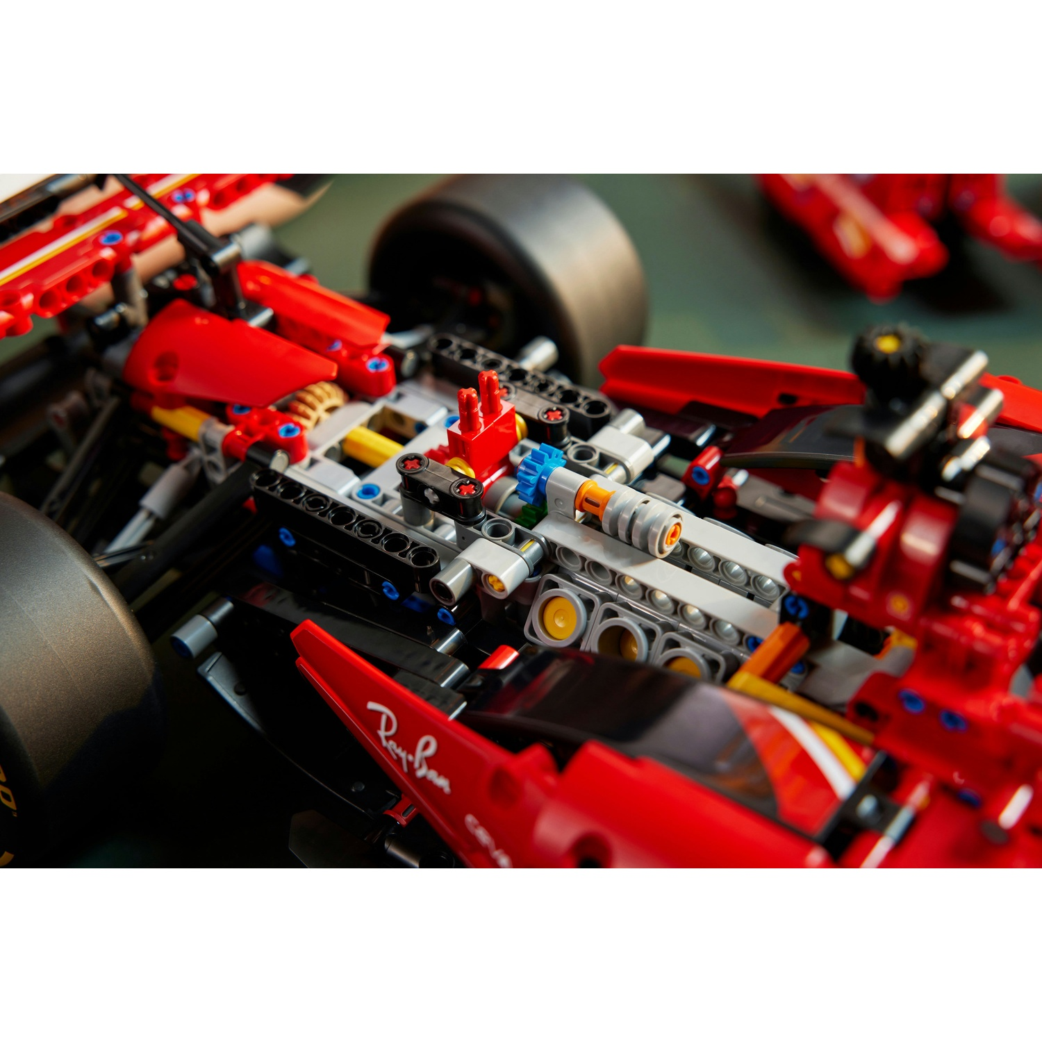 Primo piano di un'auto da corsa Lego rossa e nera. Ha un logo Ray-Ban. L'auto è su una superficie verde.