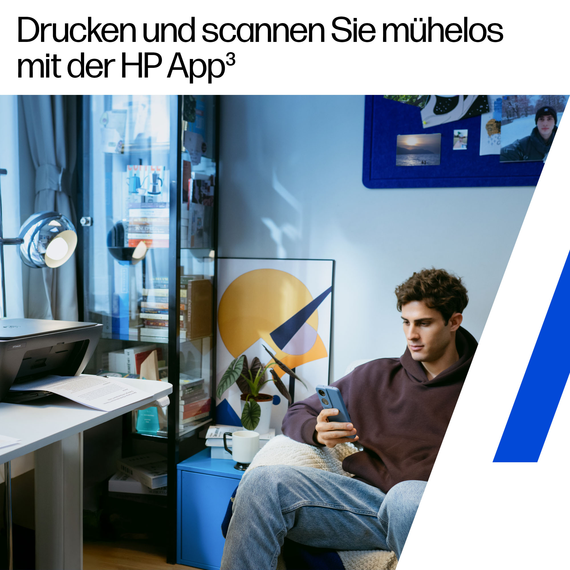Mann mit blauem Telefon, sitzt in der Nähe eines Druckers. Schreibtisch mit Papier. Bücherregale, Poster und ein blauer Beistelltisch.