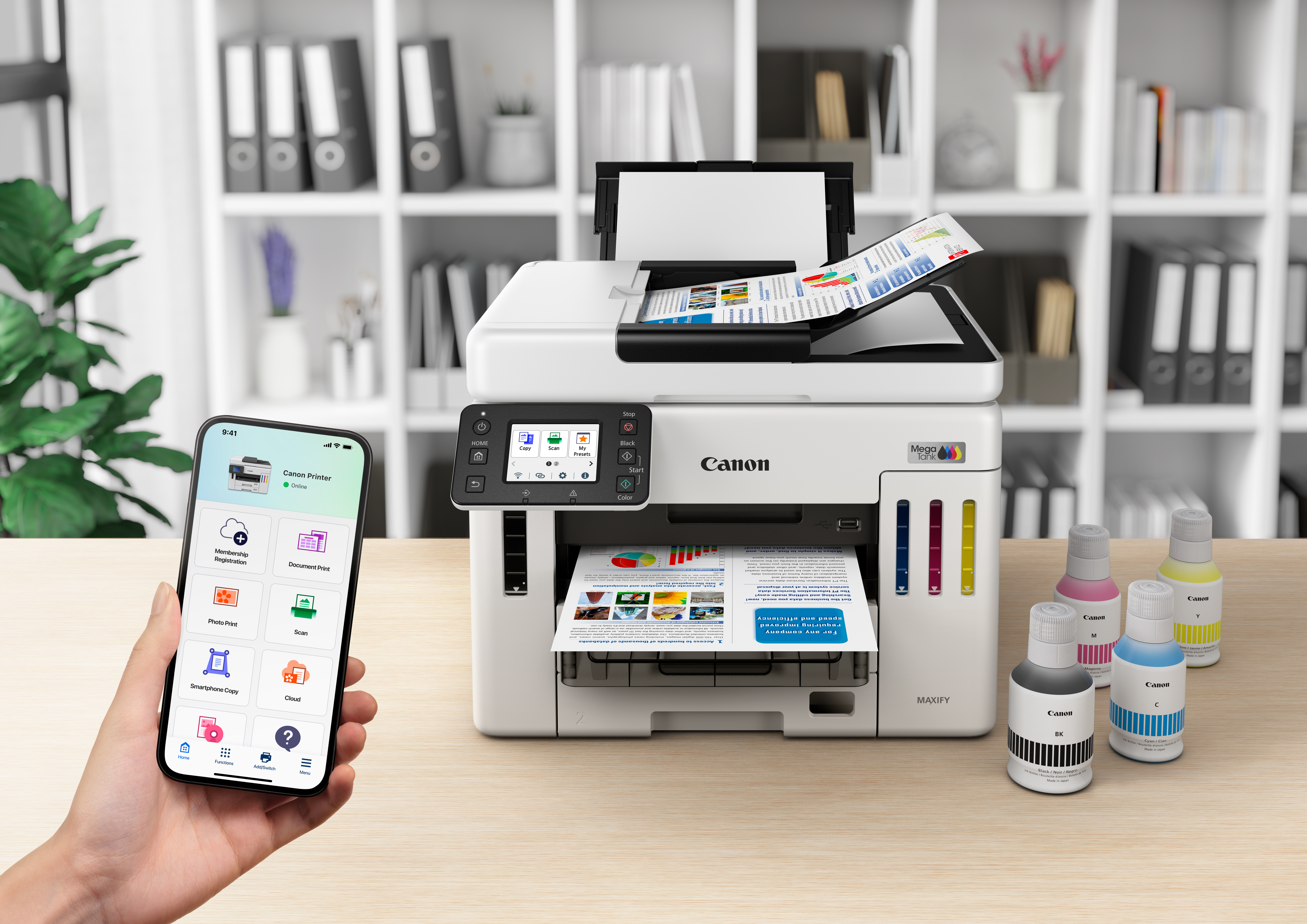 Une imprimante Canon avec sortie papier, flacons d'encre et un smartphone affichant l'application d'impression.
