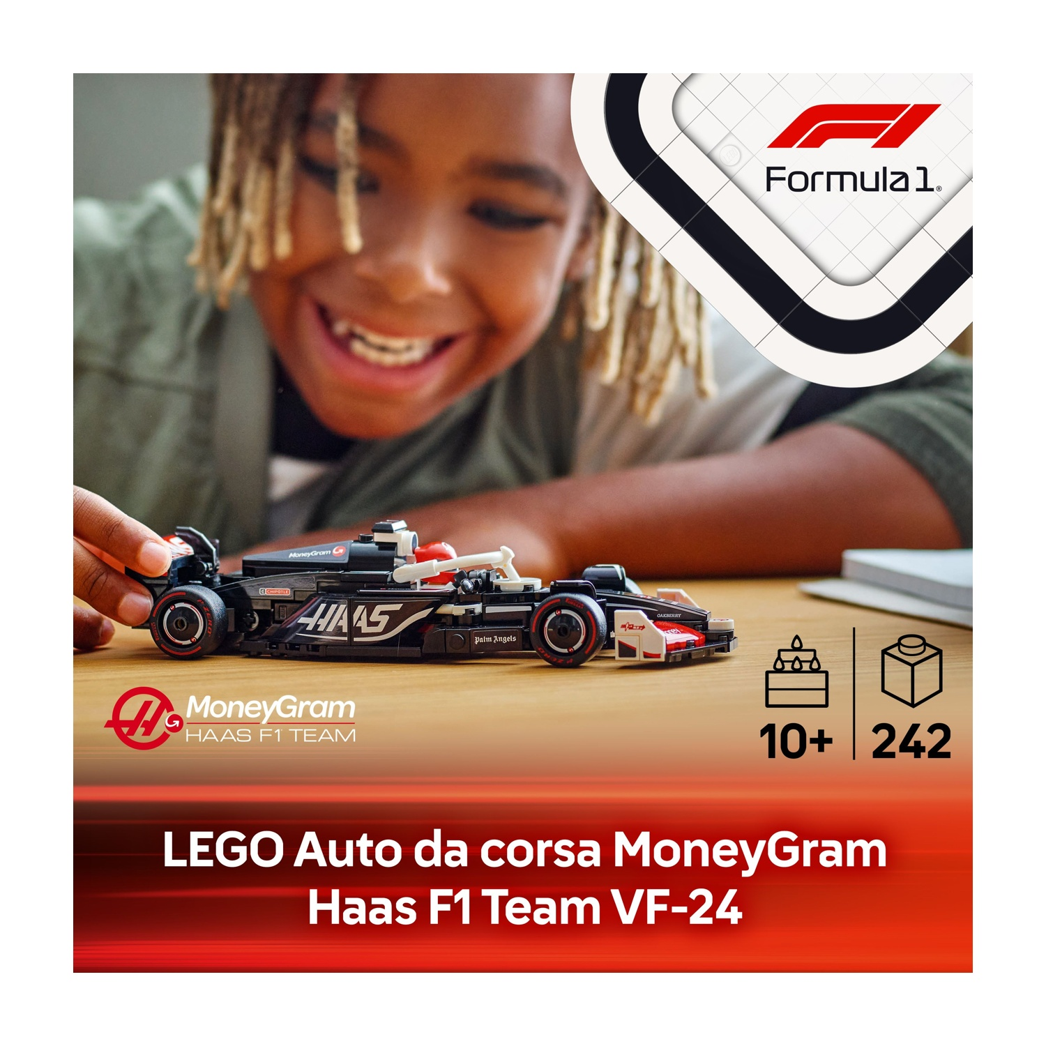 Un bambino sorride, tenendo in mano un'auto LEGO Haas F1. L'auto è nera, bianca e rossa. Lo sfondo presenta un logo e un testo della Formula 1.
