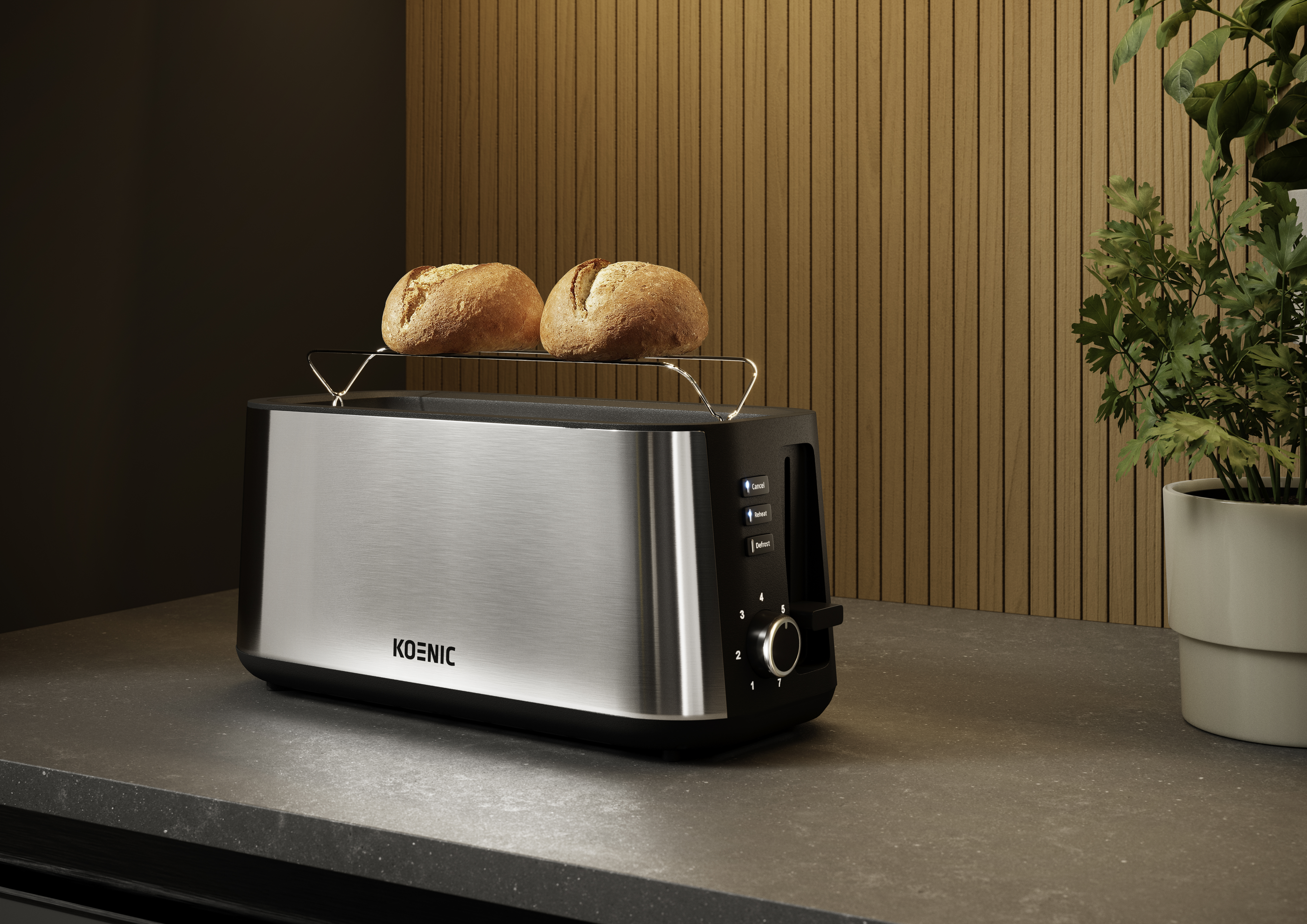 Toster ze stali nierdzewnej z dwoma opieczonymi bułkami. Toster stoi na ciemnym blacie z rośliną.