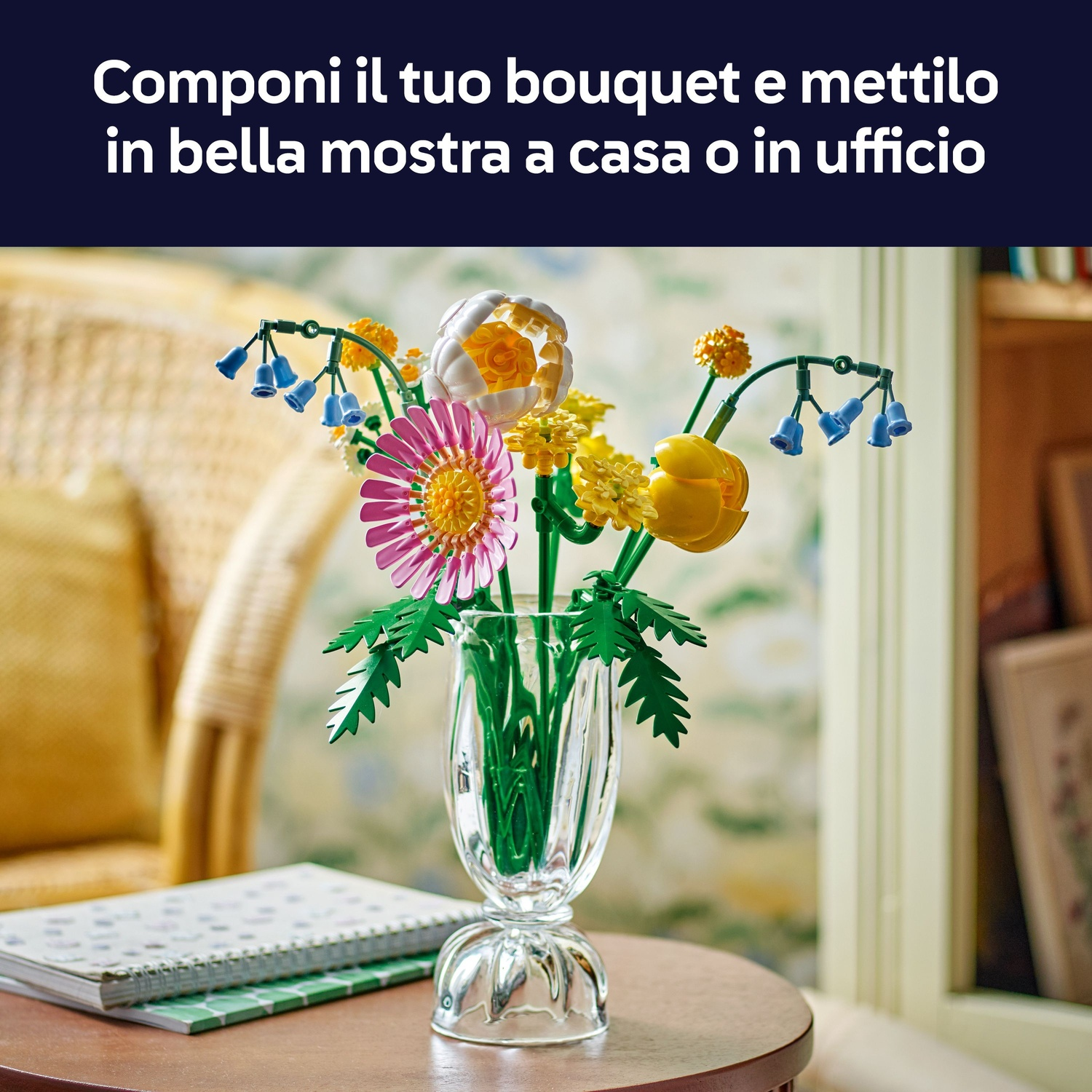 Un bouquet di fiori colorati in un vaso di vetro su un tavolo di legno. Un taccuino e una sedia sullo sfondo.