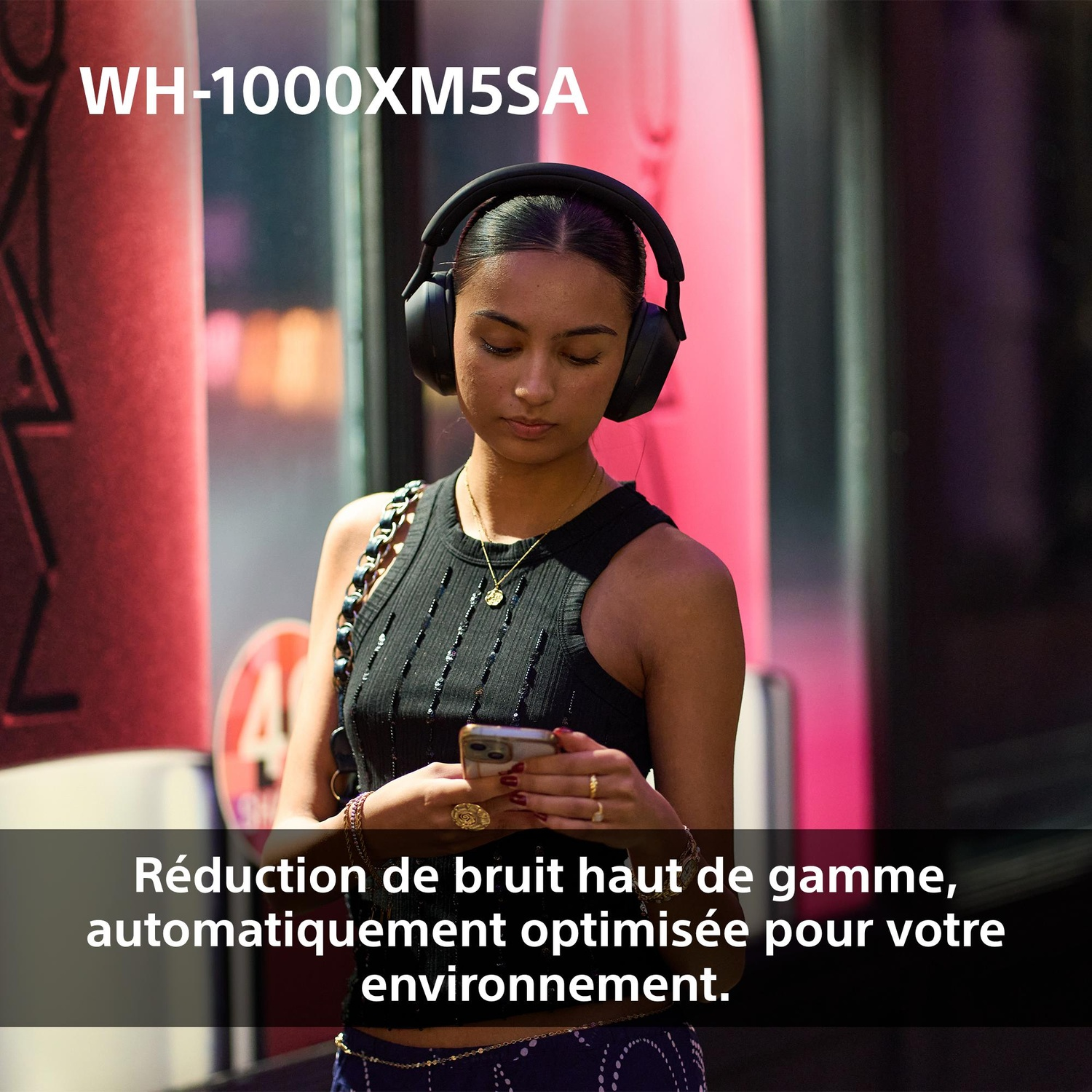 Une femme portant un casque noir et un haut noir regarde son téléphone. Le texte en bas indique : « Réduction de bruit haut de gamme ».