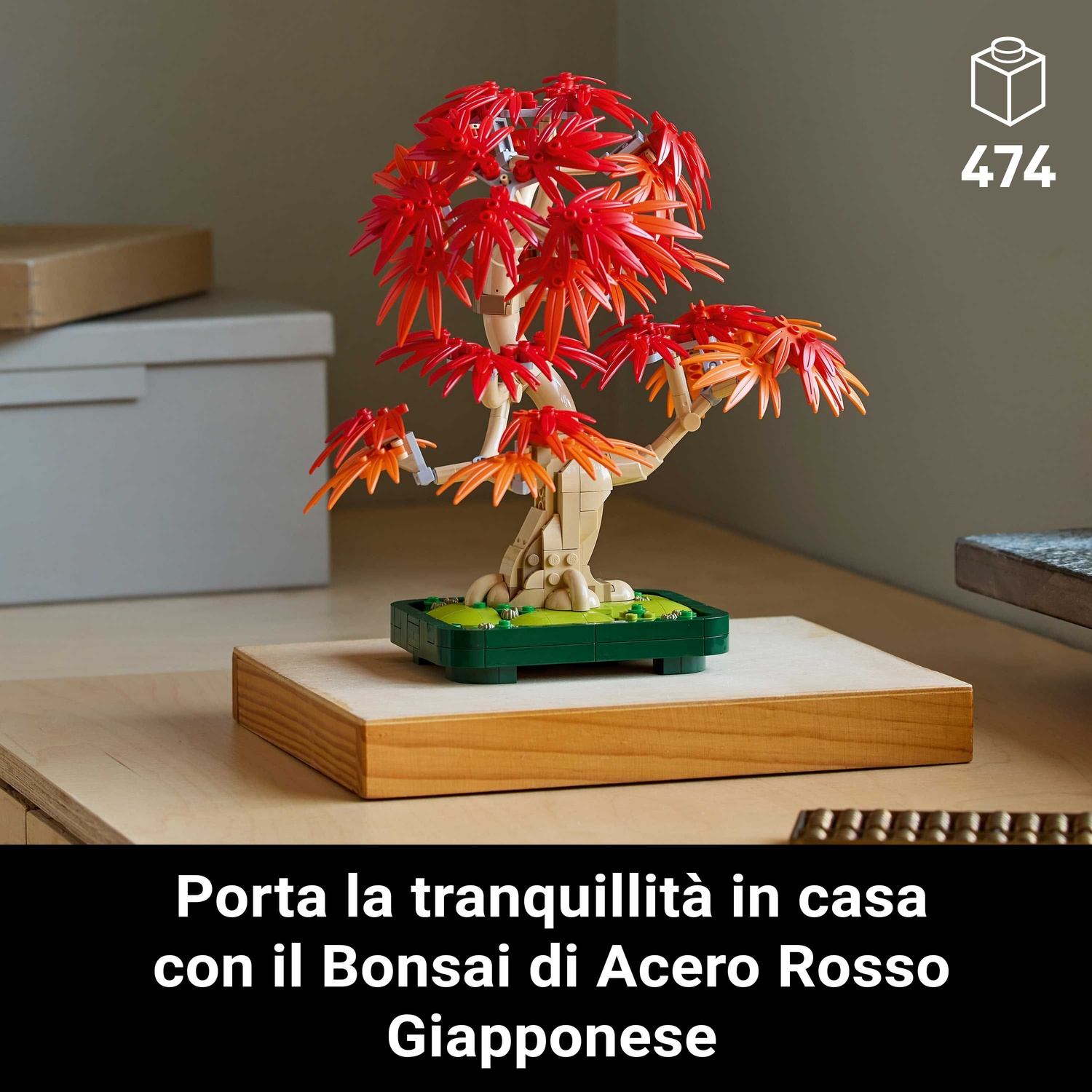 Un bonsai Lego con foglie rosse e arancioni su una base di legno. Lo sfondo mostra un armadio bianco.