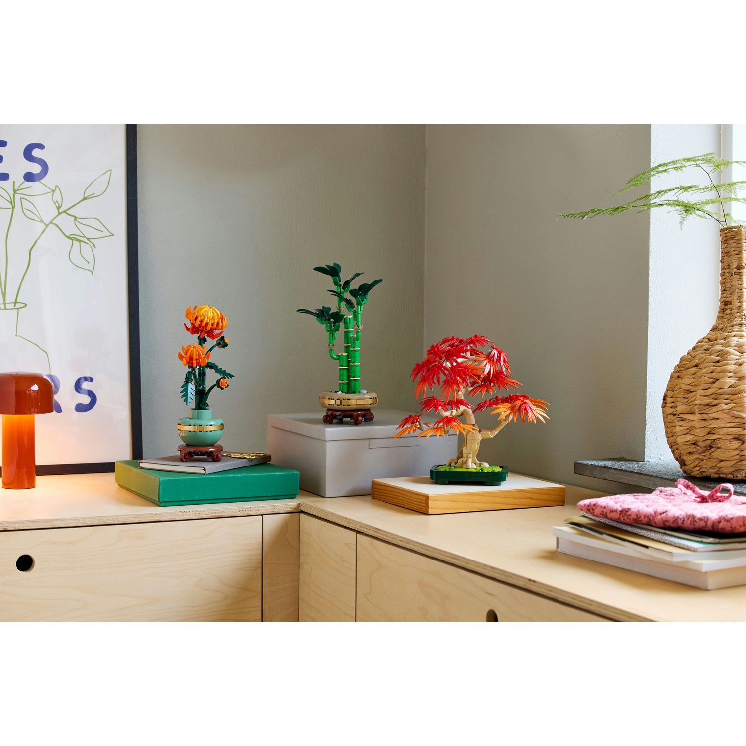 Un'esposizione di alberi bonsai e fiori Lego su una superficie in legno. Un vaso e un'opera d'arte sullo sfondo.