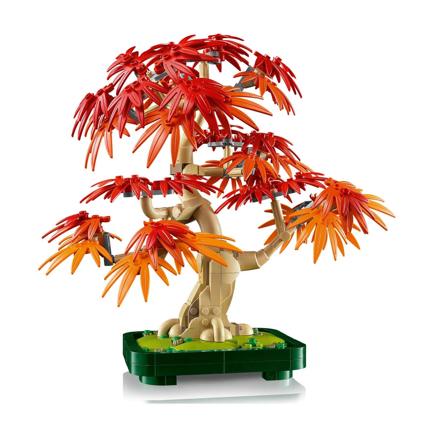 Un bonsai Lego con foglie rosse e arancioni. L'albero si trova in un vaso verde su una superficie bianca, con sfondo bianco.