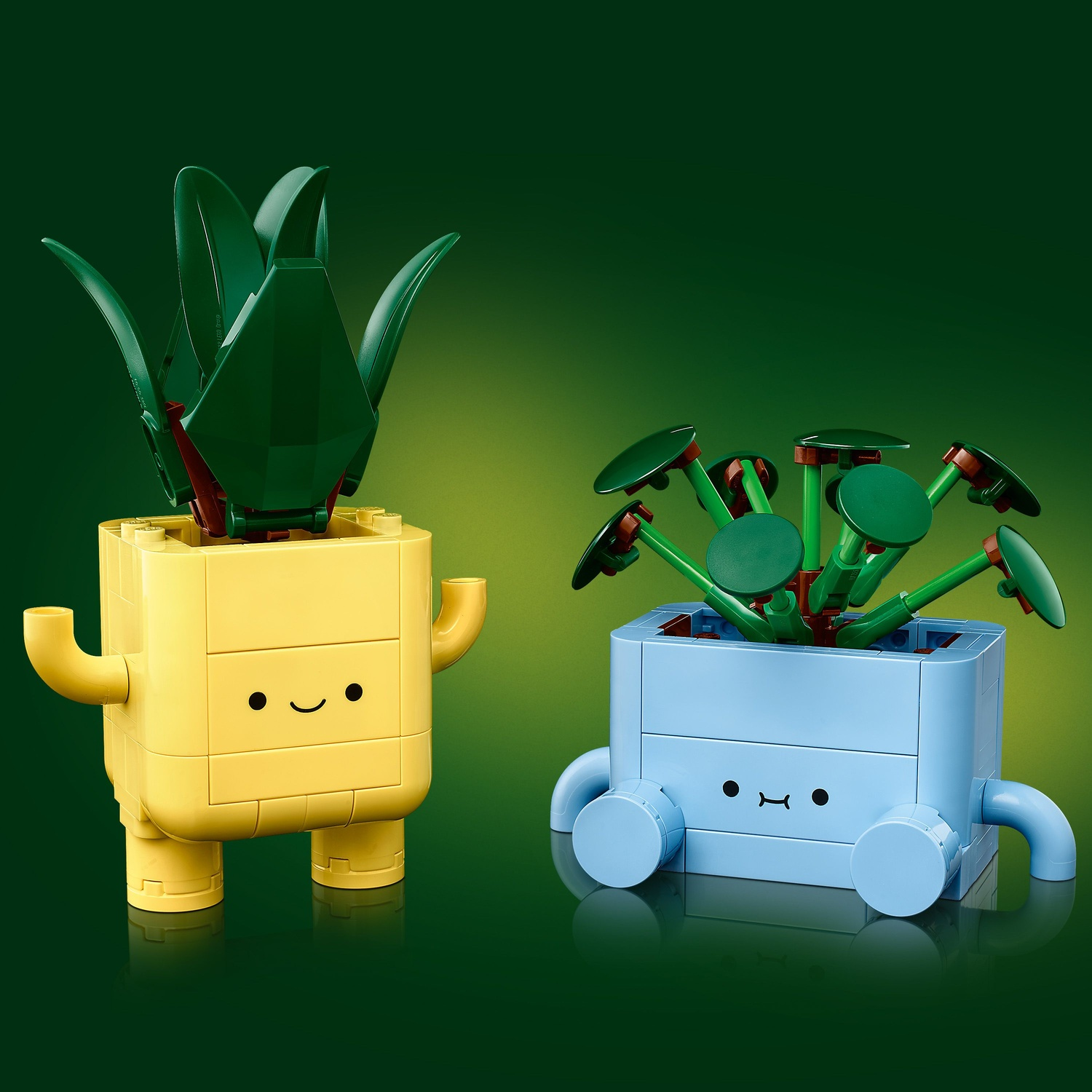 Due vasi Lego. Vaso giallo con foglie verdi e vaso blu con steli verdi e foglie rotonde, su sfondo verde.