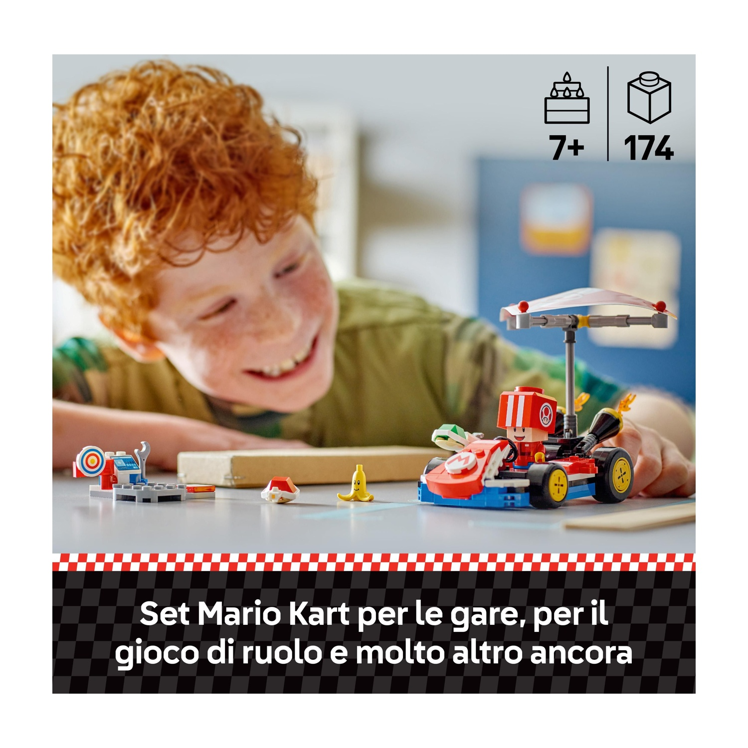 Un bambino sorride a un set di Mario Kart. Il set include un kart rosso e blu e vari pezzi Lego. Lo sfondo è sfocato.