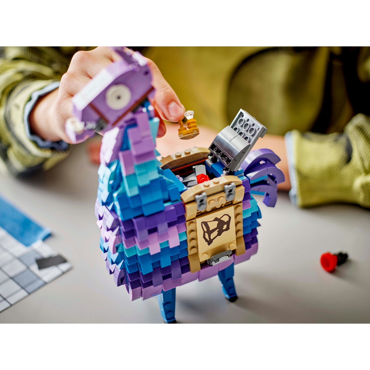 Una persona sta aprendo una pignatta a forma di lama Lego. La pignatta è blu, viola e marrone. Un piccolo pezzo Lego marrone è nella mano della persona.