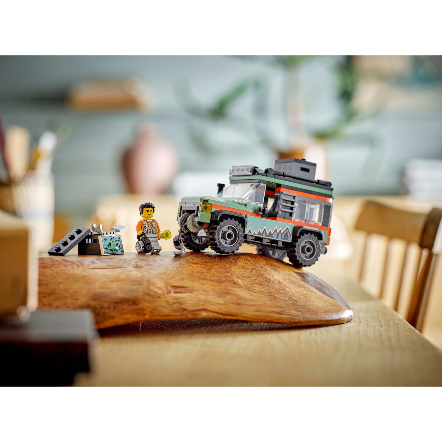 Set Lego di un SUV verde e nero, un personaggio Lego e piccoli accessori, su un tavolo di legno.