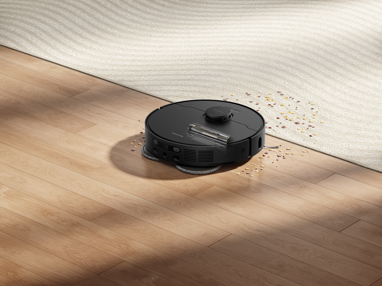 Una aspiradora robot negra sobre un piso de madera cerca de una alfombra. Los escombros están esparcidos. La aspiradora está limpiando.